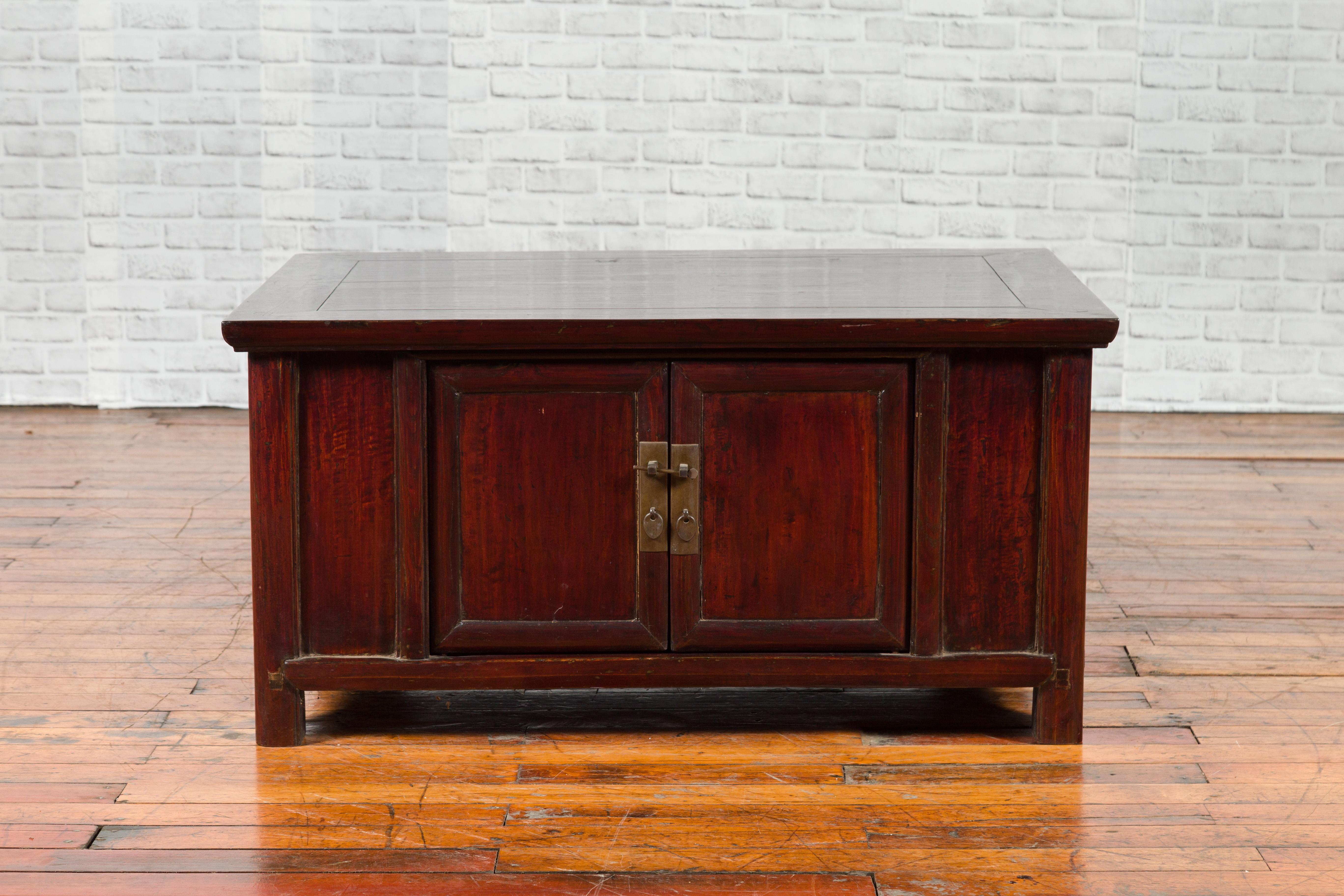 A Chinese Qing dynasty low cabinet from the 19th century, with two doors and reddish brown lacquer. Created in China during the 19th century, this Qing low cabinet could be very well used as a coffee table. Featuring a rectangular top with central