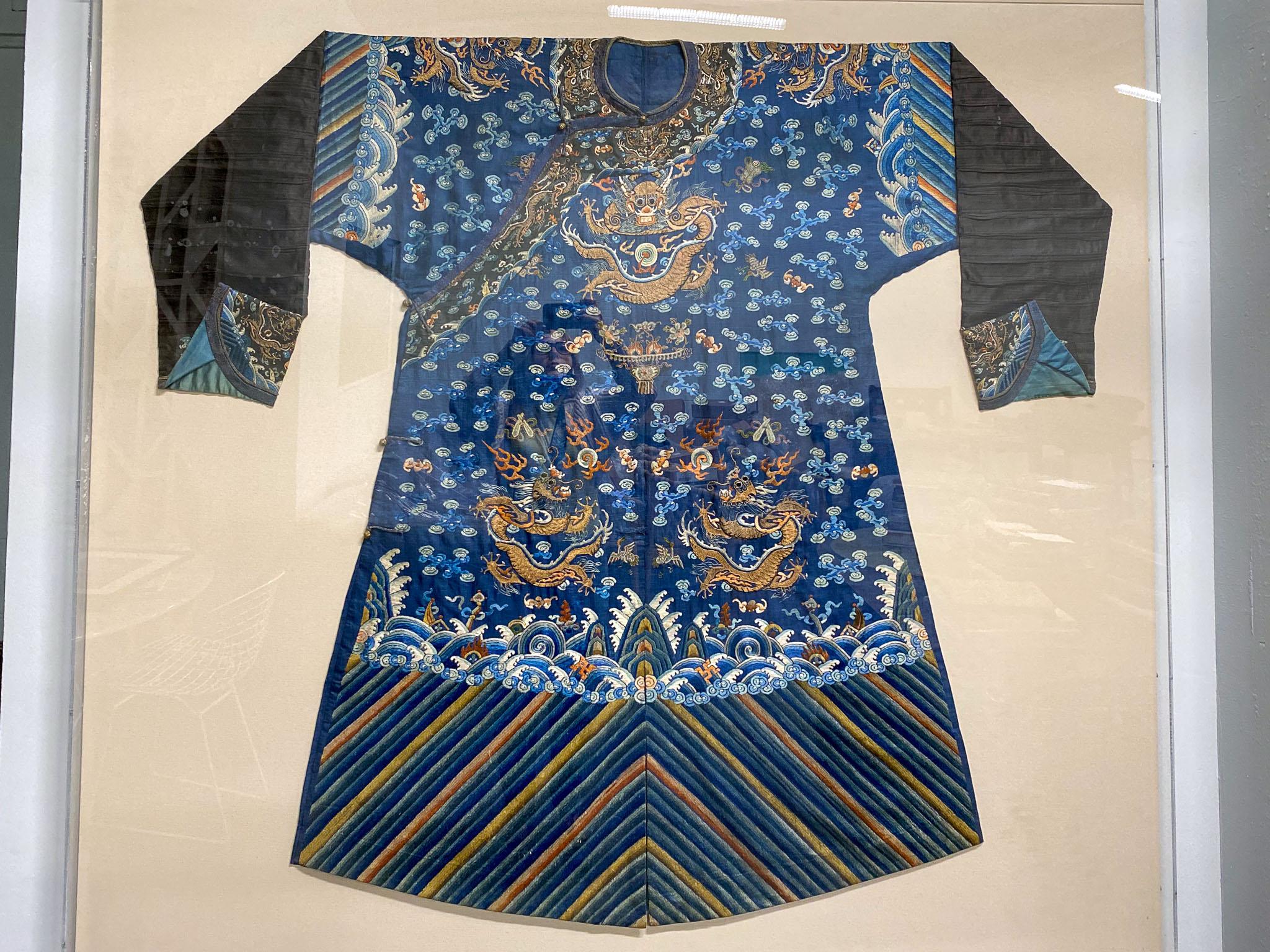 Beautifully crafted and sewn Chinese robe. Complete with dragons and other symbolism, this blue robe has been framed out in an acrylic shadow box. 
Purchased from a collection with other fine Chinese antiquities and robes, this piece has been