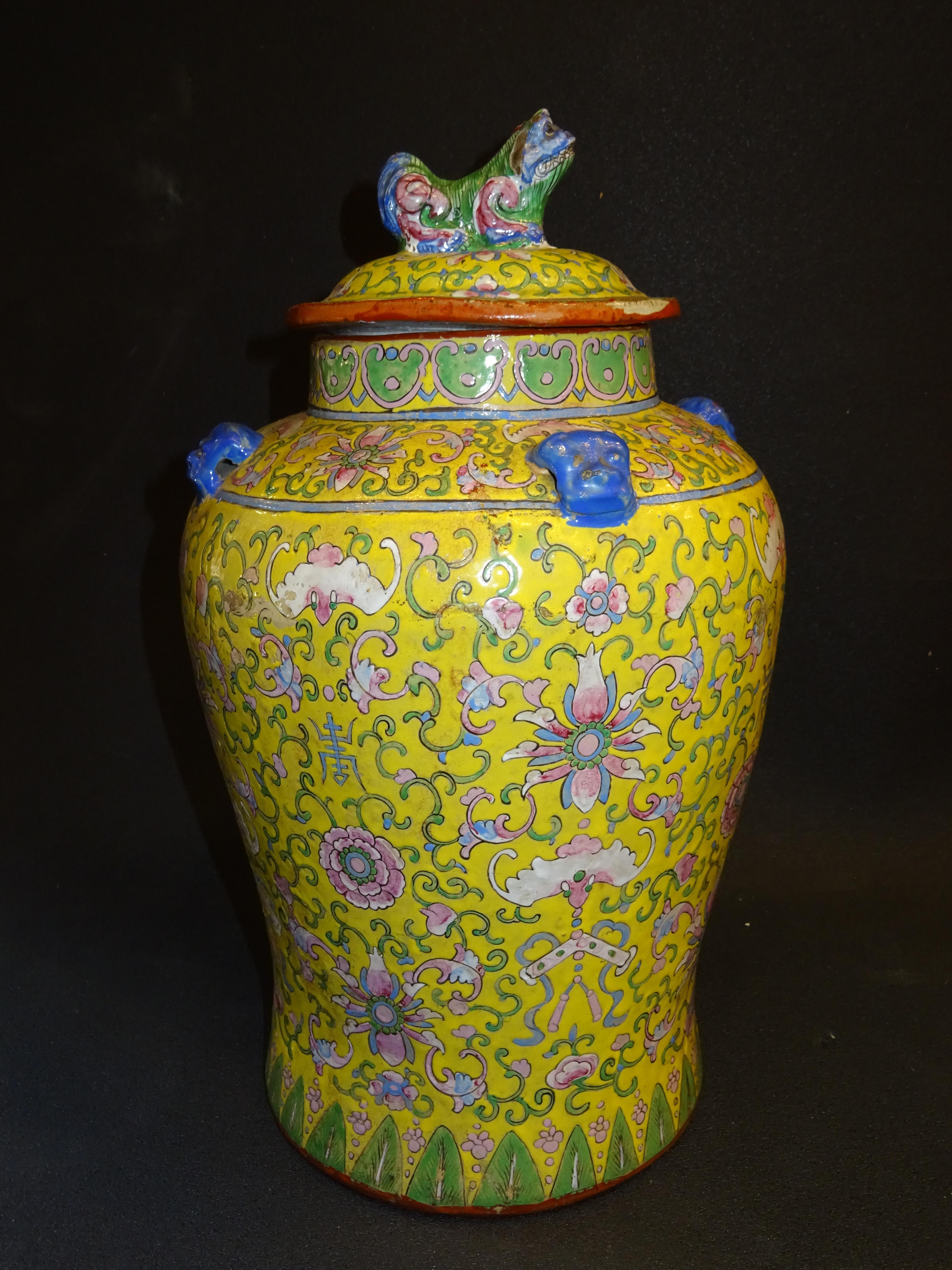 One of a kind Chinese ceramic vase with a foo lion lid. On a marvelous yellow, hand painted chrysanthemums, peonies or different Chinese symbols in shades of pink, green and blue.
It has an amazing lid with a foo lion on the top, there is also 3