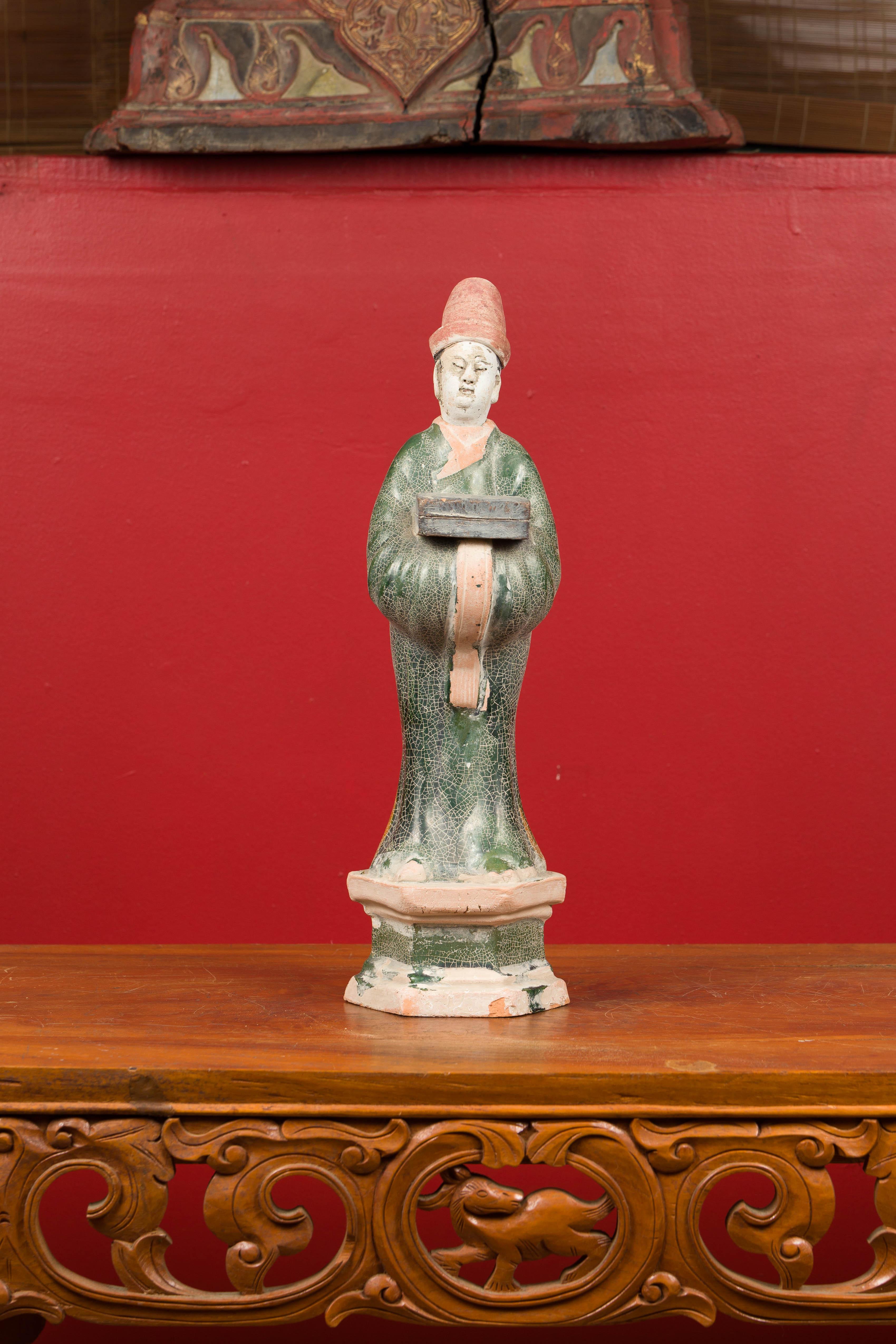 A petite antique Chinese Ming Dynasty period glazed terracotta statue from the 17th century, depicting an official holding a box. Presenting a nice patina, this Ming Dynasty statue attracts our attention with its red, green and white tones. The