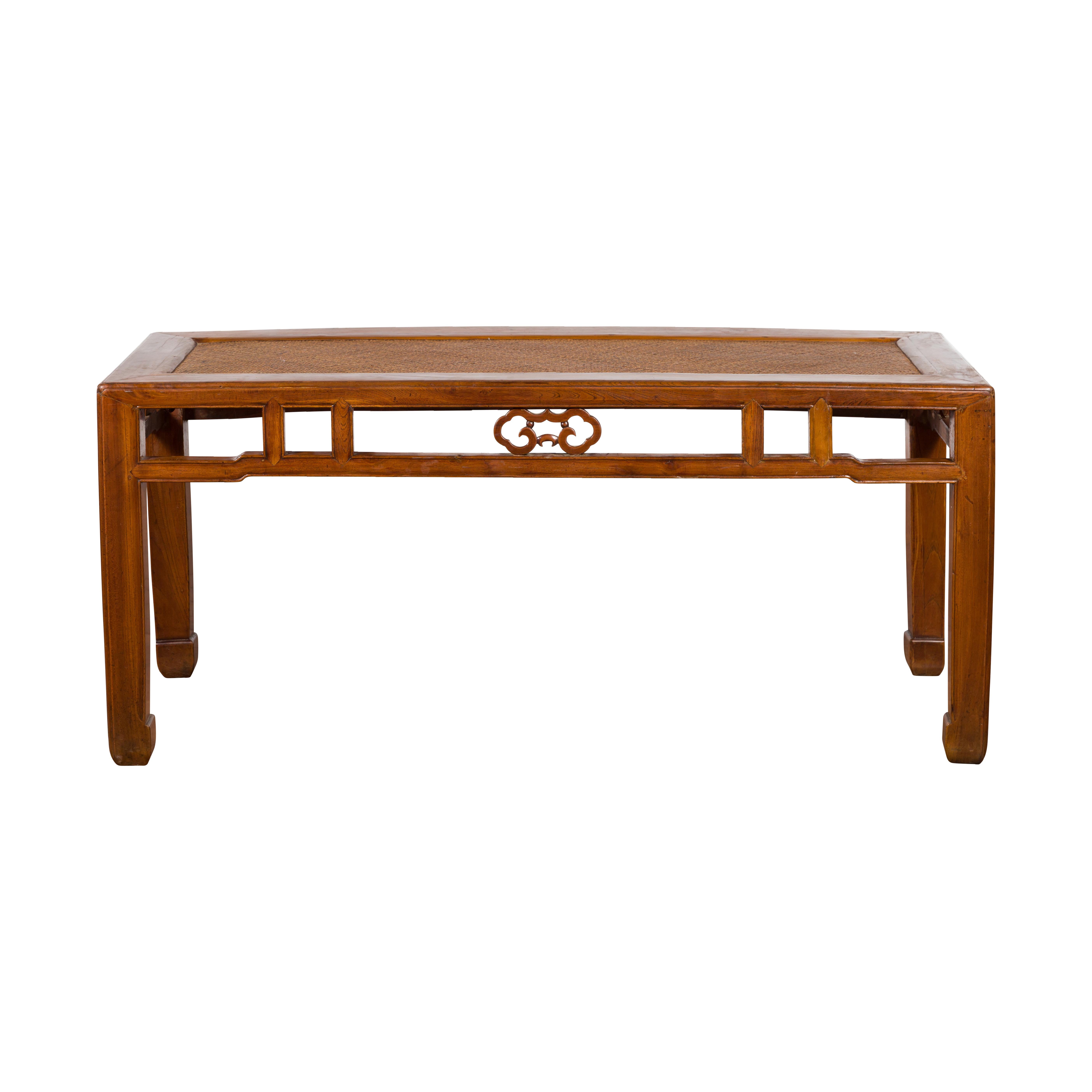 A Chinese Qing Dynasty period coffee table from the 19th century, with rattan top and horse hoof legs. Created in China during the Qing Dynasty, this wooden coffee table features a rectangular top with rattan inset, sitting above a pierced apron