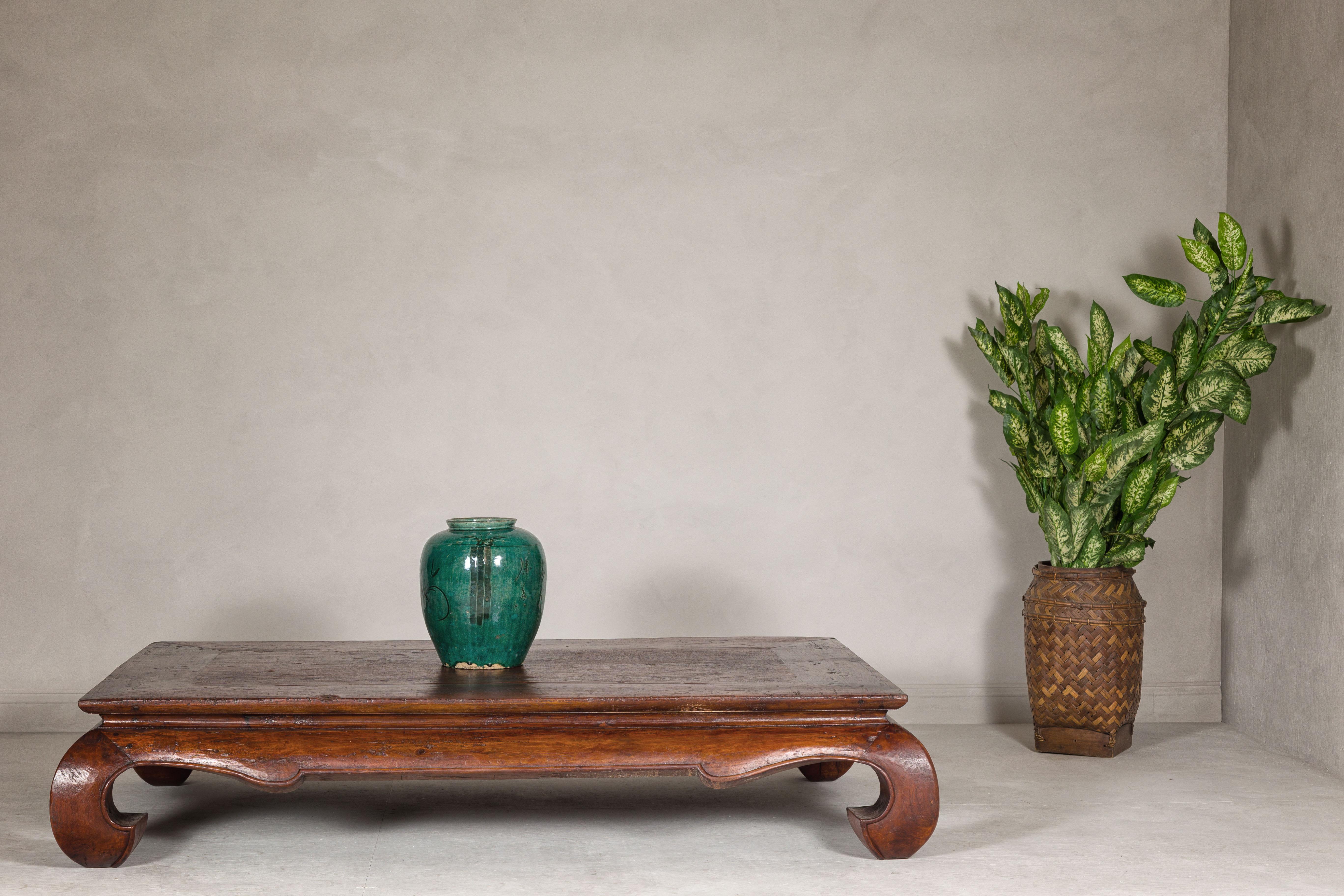 A Qing Dynasty period low Kang coffee table from the 19th century with chow legs and weathered, rustic patina. This Qing Dynasty period low Kang table, transformed into a contemporary coffee table, bridges the past and present with its weathered and