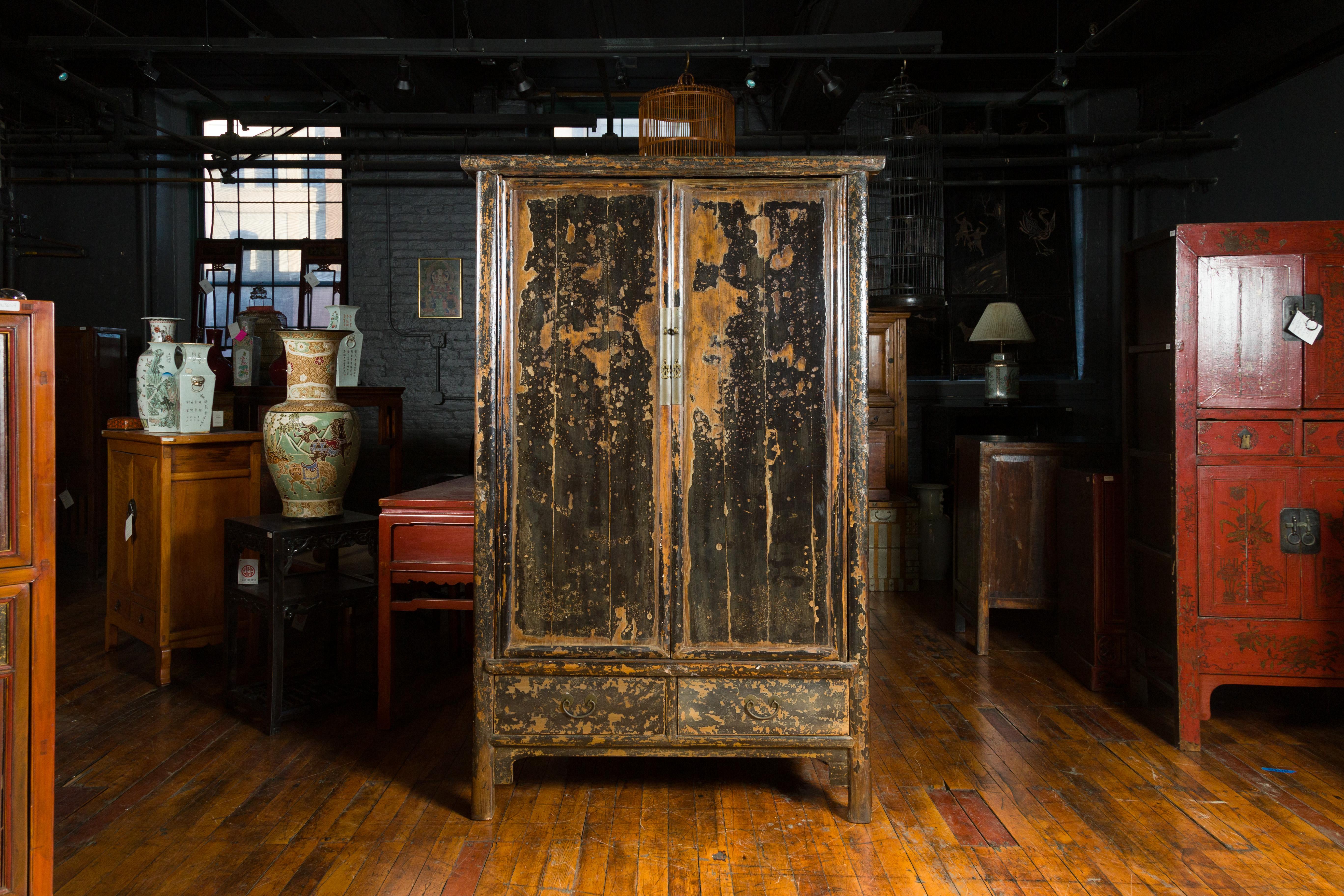 A Chinese Qing Dynasty period black lacquered cabinet from the 19th century, with original finish, doors and drawers. Crafted during the Qing Dynasty in the 19th century, this authentic Chinese cabinet retains its original black lacquered finish,