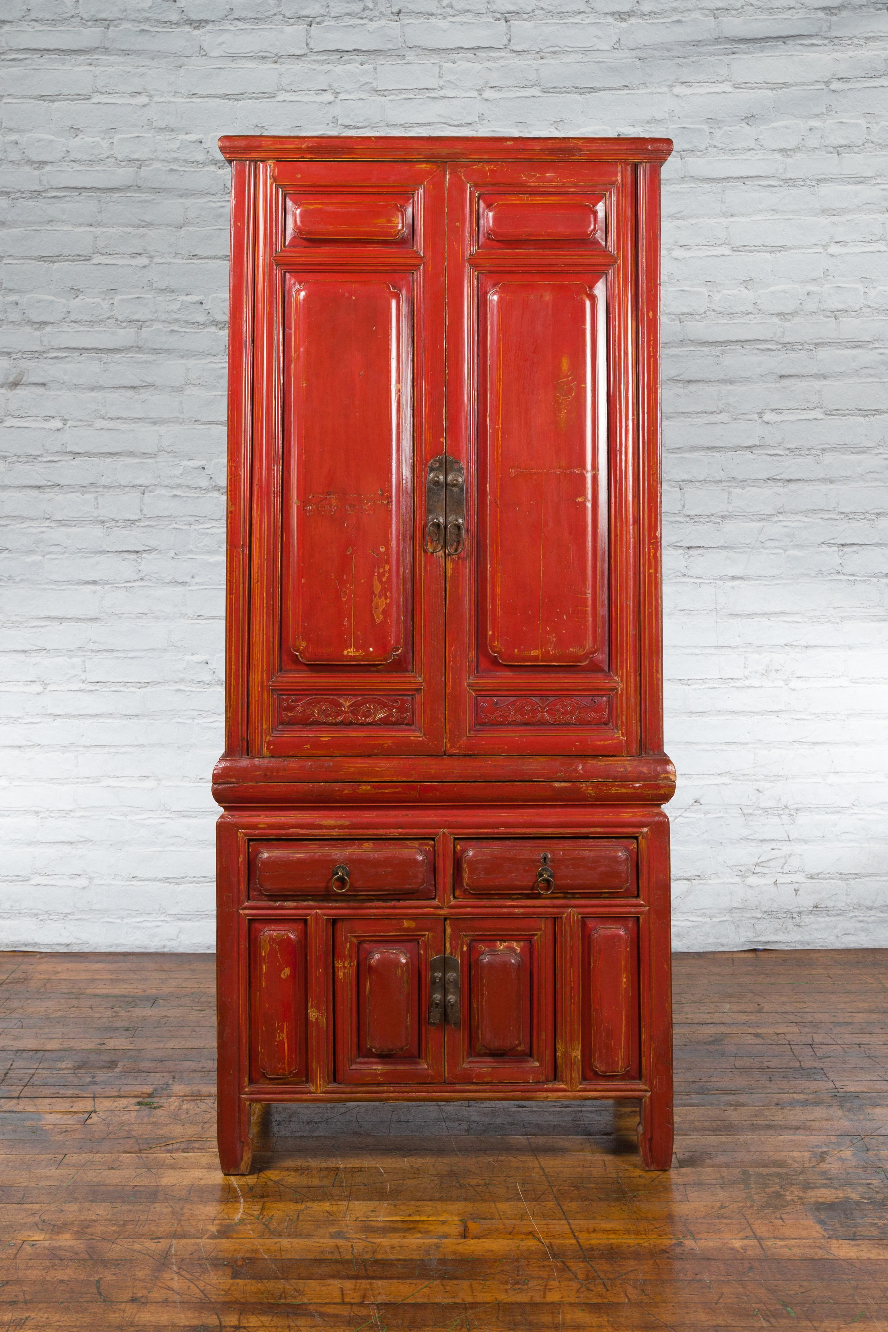 A Chinese late Qing Dynasty period red lacquered compound cabinet from the early 20th century, with raised panels and carved friezes. Created in China during the late period of the Qing Dynasty in the early 20th century, this compound cabinet