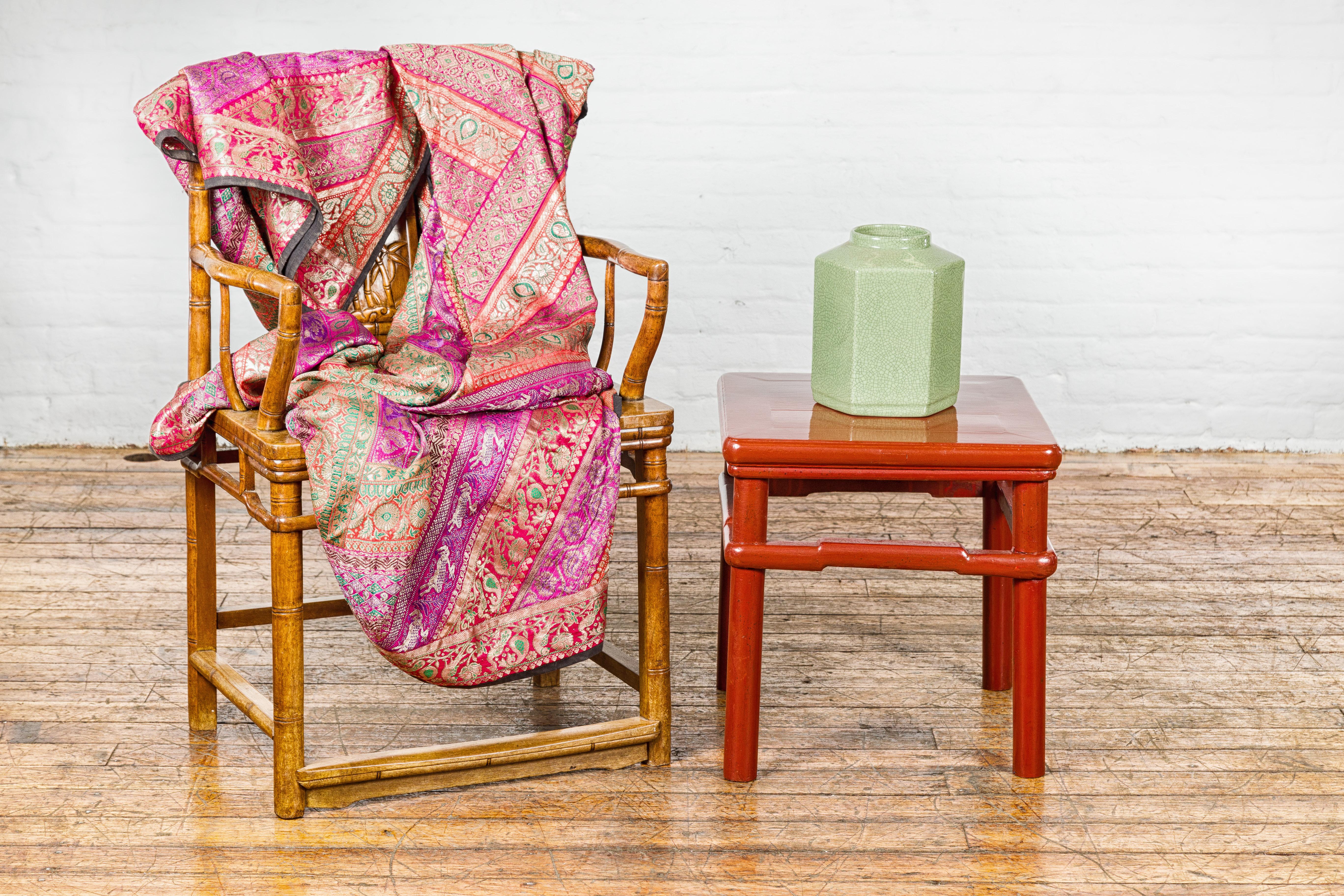 A Chinese Qing Dynasty period red lacquer side table from the 19th century with humpback stretcher and cylindrical legs. This Chinese Qing Dynasty period side table, originating from the 19th century, is a remarkable fusion of cultural heritage and