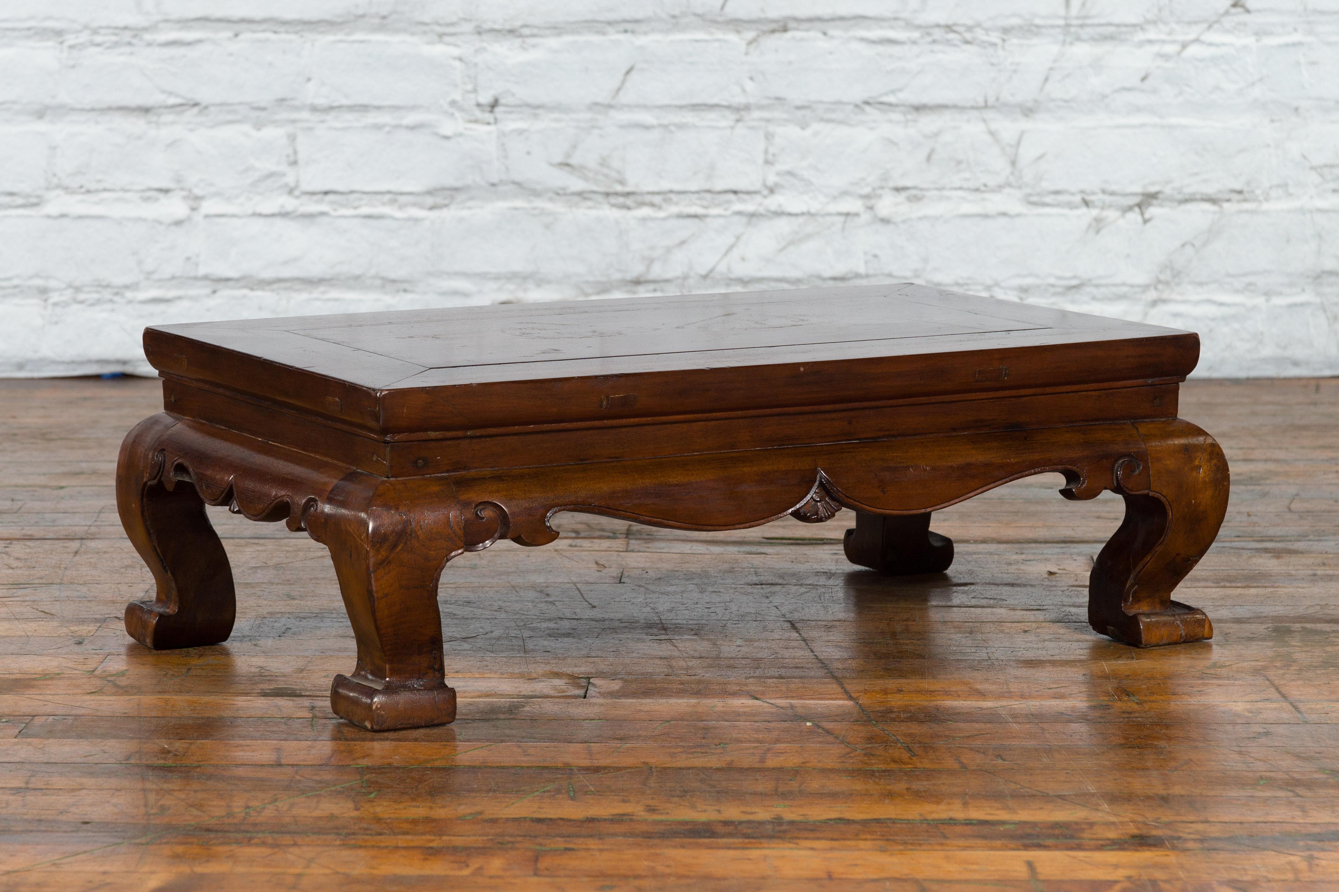A small Chinese Qing Dynasty period coffee table from the 19th century, with chow leg design and carved apron. Created in China during the Qing Dynasty, this small coffee table features a rectangular top with central board, sitting above a carved