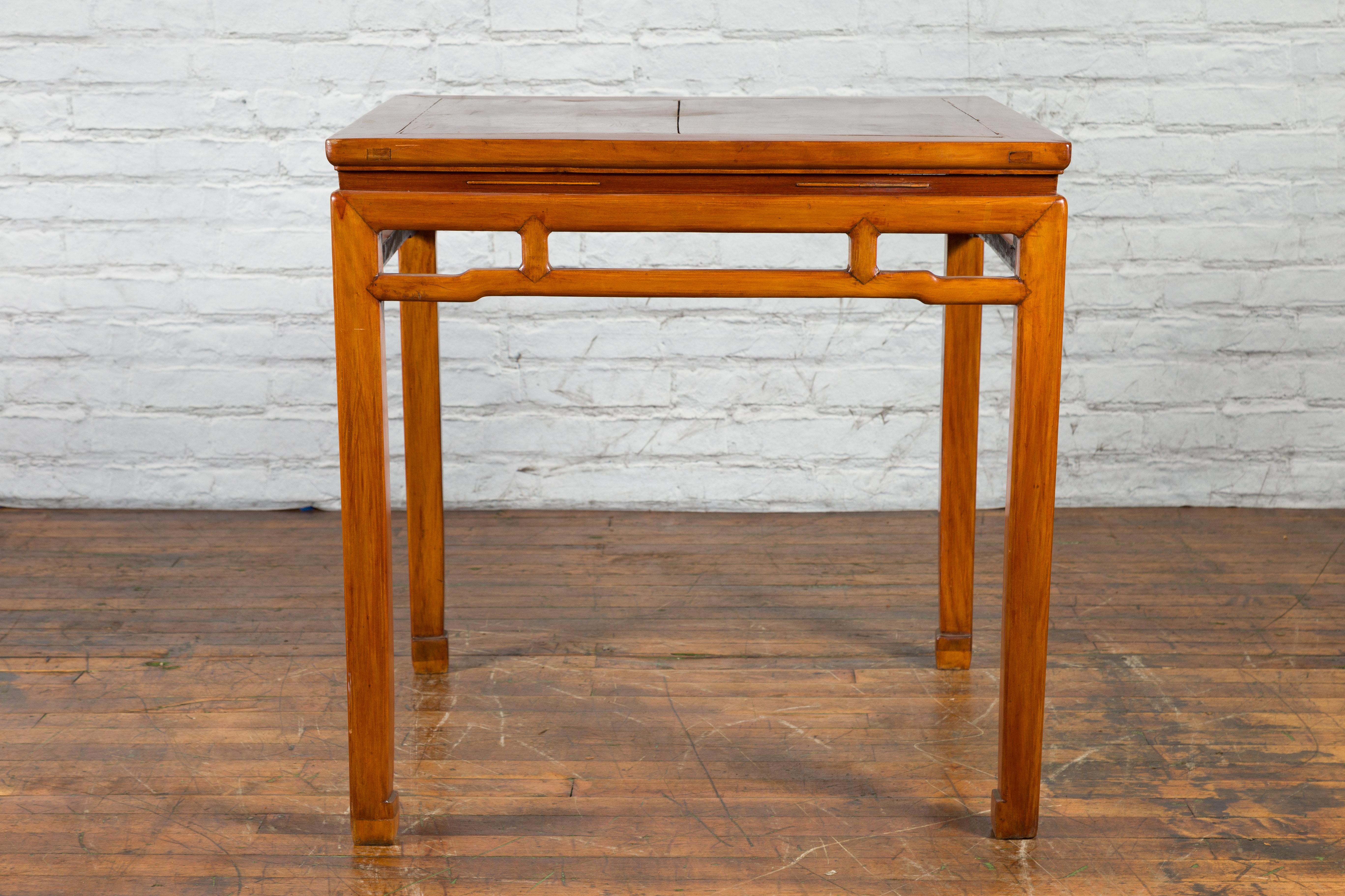 A Chinese Qing Dynasty period square shaped fruitwood table from the 19th century, with light lacquer, humpback stretchers and horse hoof legs. Created in China during the Qing Dynasty, this fruitwood table features a square planked waisted top