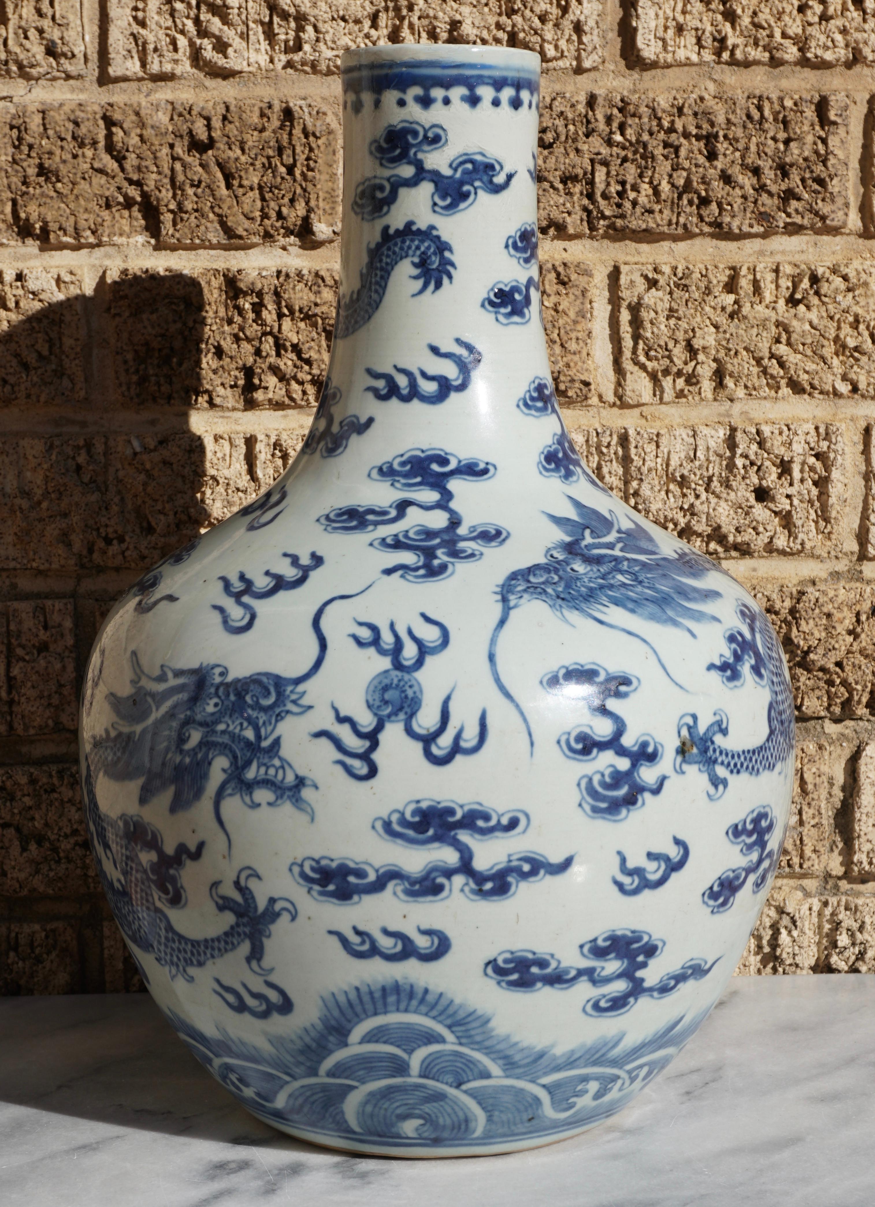 19th century blue and white ceramic porcelain bottle neck vase with two dragons chasing the elusive pearl of wisdom through the clouds over waves. Rim has repairs and displays beautifully. Hand painted in beautiful underglaze. 

Height:15