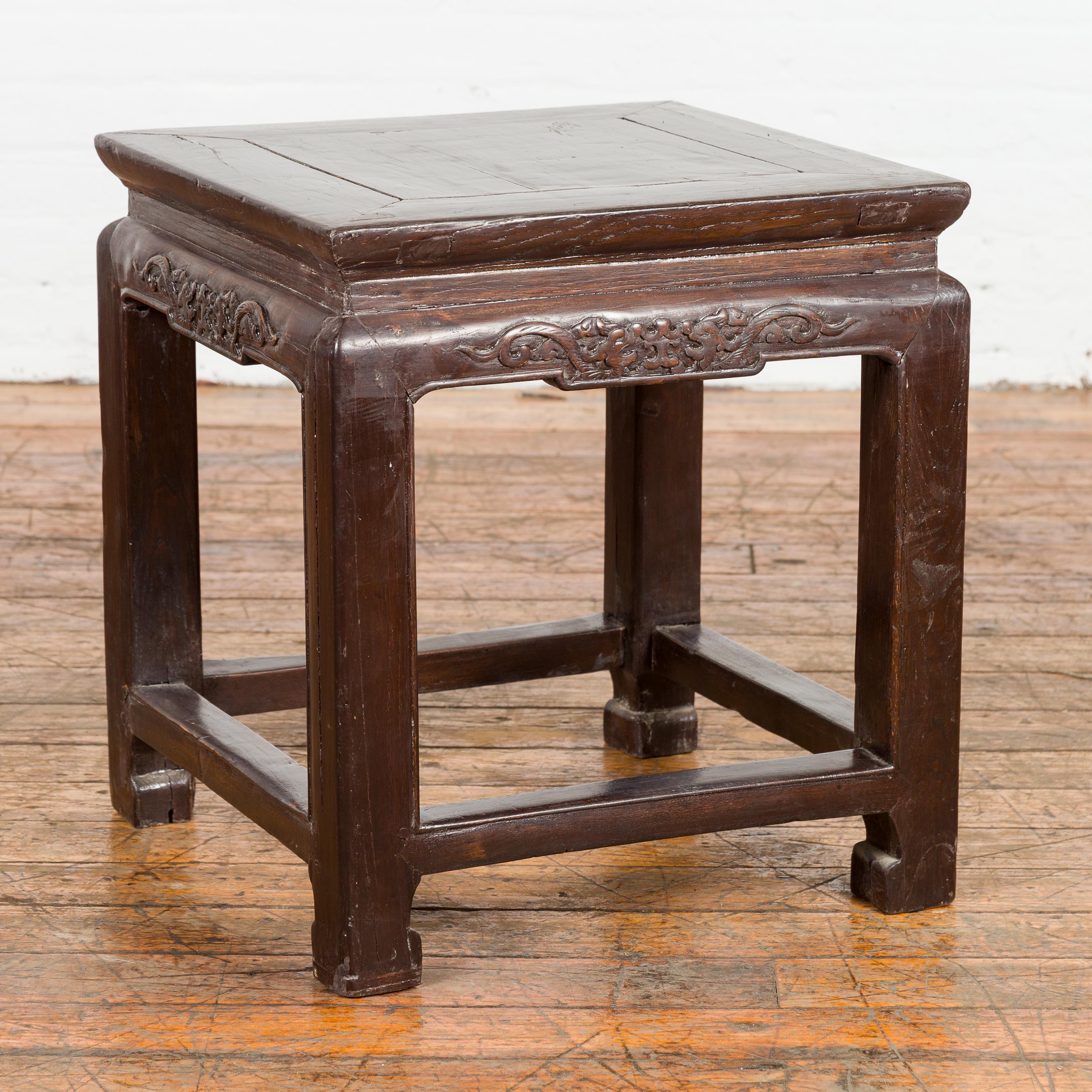 A late Qing Dynasty period side table from the early 20th century with waisted top, carved apron, horse hoof legs, and side stretchers. This late Qing Dynasty period side table, hailing from the early 20th century, is a true testament to the