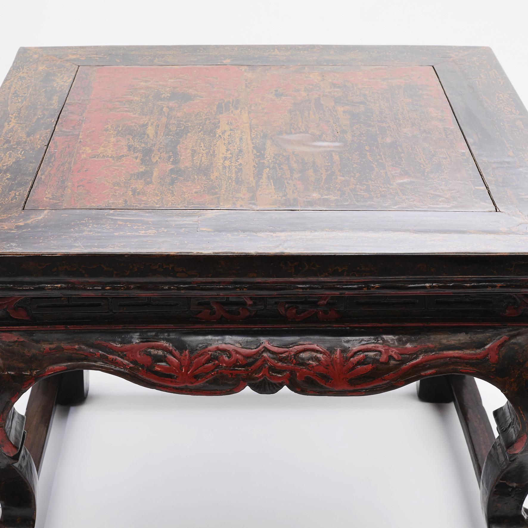 Chinese center table. Original condition and black / red lacquer.
Finely carved scalloped apron accented with scrolling foliage motifs.
Resting on four saber legs ending in claw and ball.
The table features its original patina with wear according to