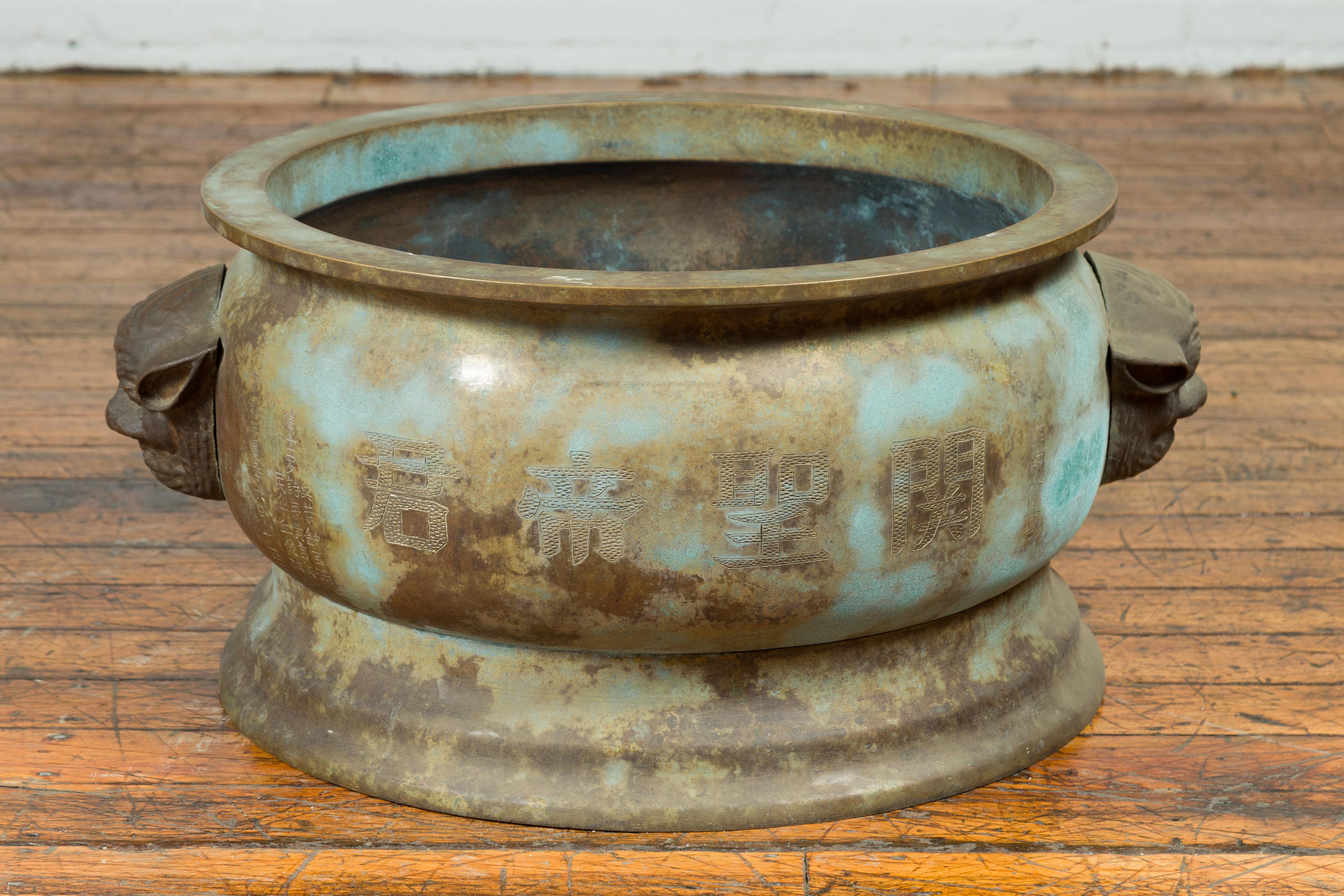 An antique Chinese bronze oversized planter from the 19th century, with mythical animal handles. Crafted in China during the Qing Dynasty, this oversized bronze planter features lateral mythical animals handles allowing the piece to be moved more