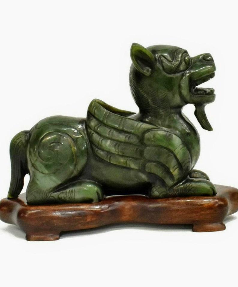 A magnificent Chinese carved spinach green jade chilong dragon sculpture, resting on fitted hardwood stand. 

Rich deep bright green color with molten shades of lighter pale green, exceptionally carved, with intricate detail throughout. The