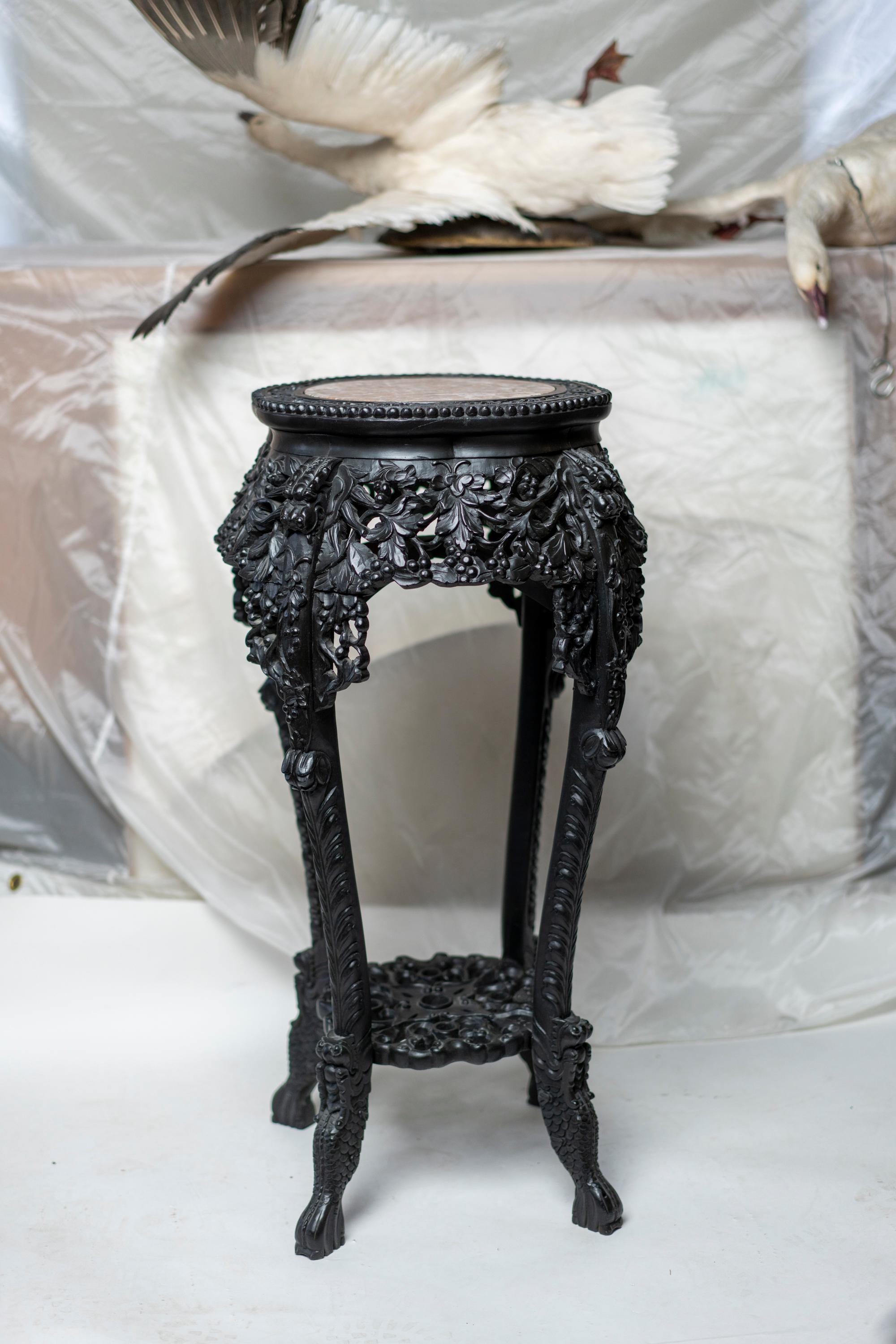 Chinese carved wood pedestal inset with marble top over elaborately carved dragon scale
legs with stylized feet.