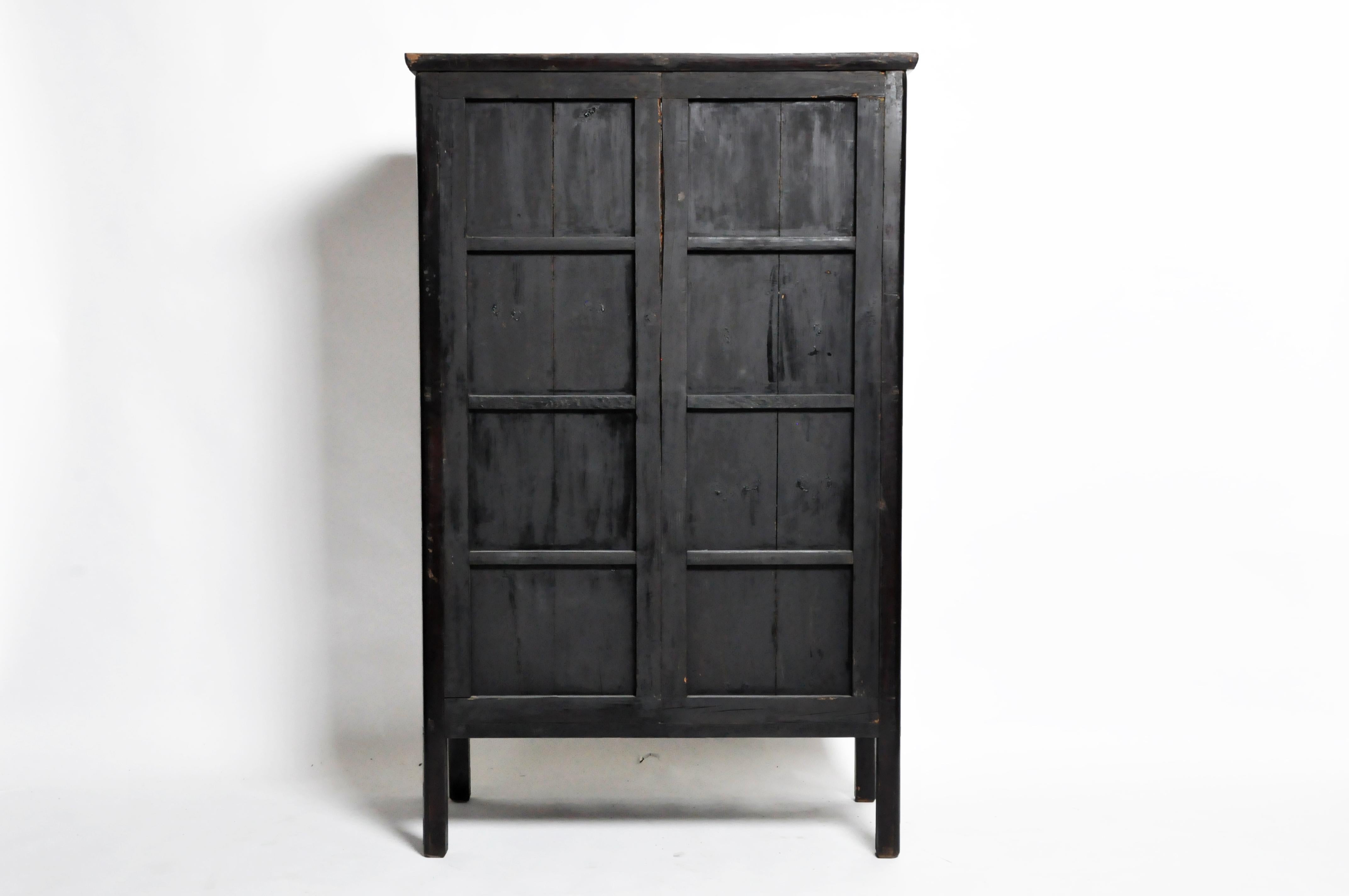 This cabinet is from Zhenjiang, China and was made from wood and black lacquer, circa early 19th century. This piece features a pair of bi-fold doors, 2 shelves, 4 drawers, and a hidden storage compartment for additional storage. The piece has been