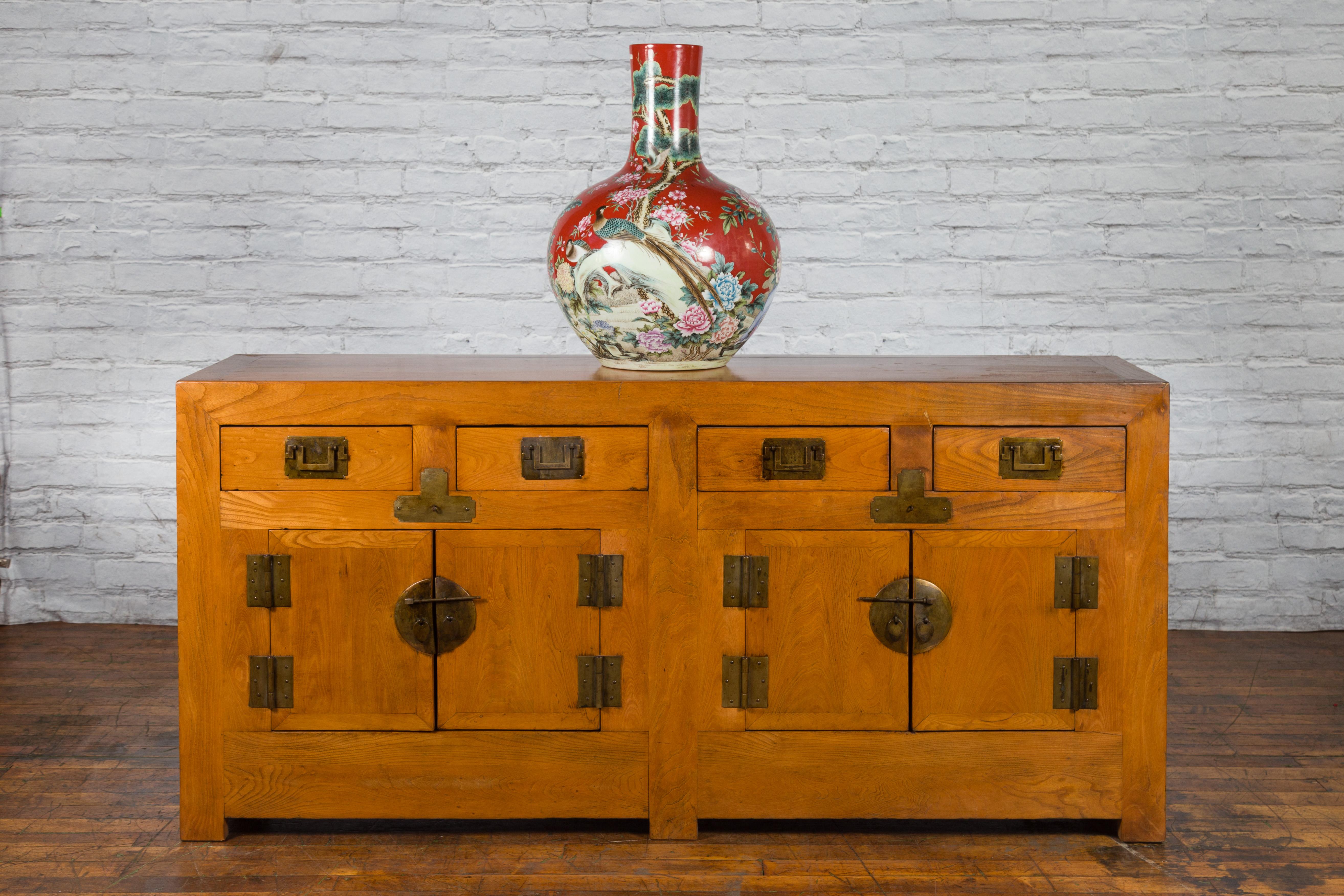 A Chinese Qing Dynasty period natural elmwood sideboard from the 19th century, with four drawers and four doors. Created in China during the Qing Dynasty, this elm sideboard features a rectangular top sitting above four drawers over four doors.