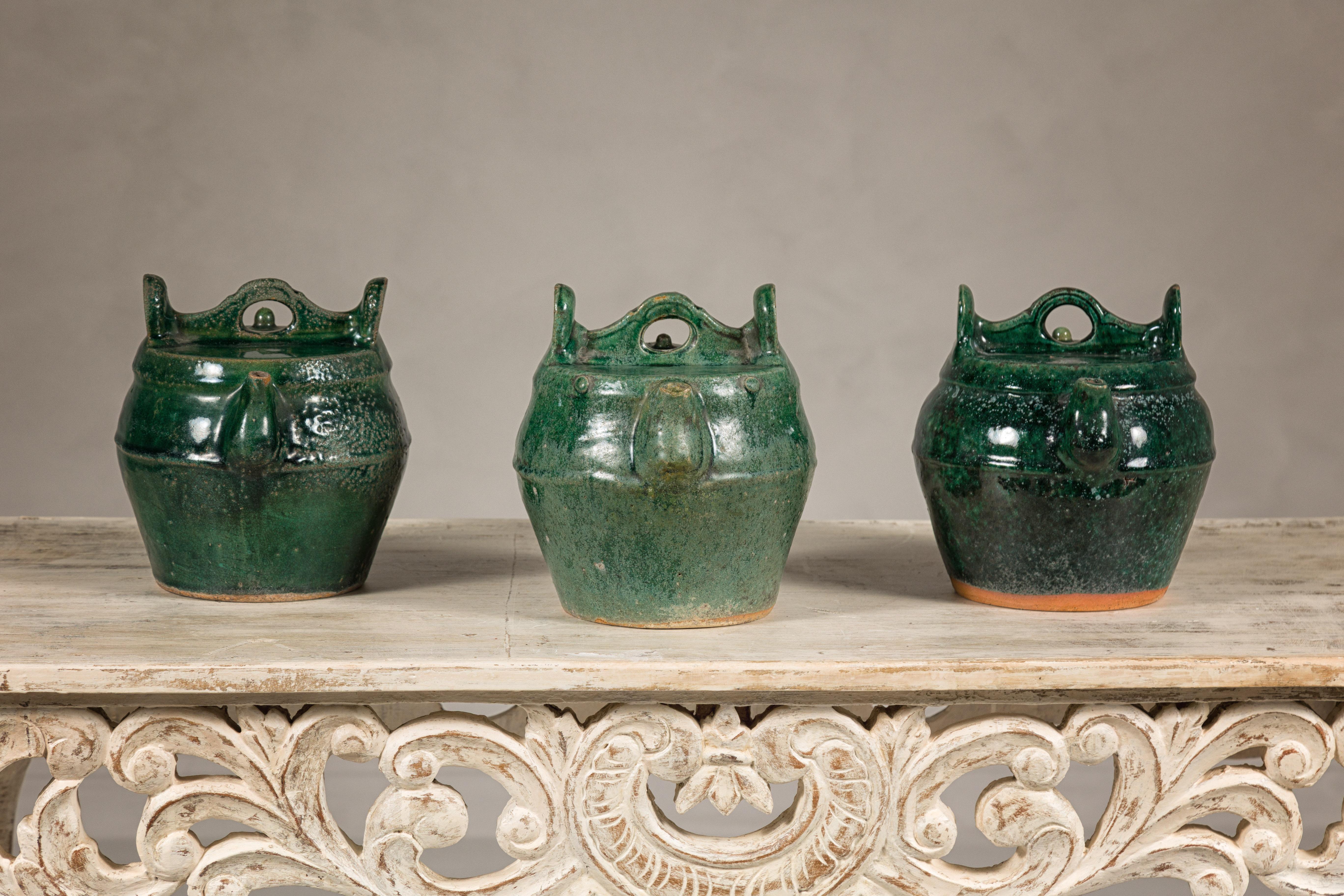A Qing Dynasty period green glaze Shiwan ware ceramic teapot from the late 19th century. Born in the late 19th century during the Qing Dynasty, these exquisite Shiwan ware ceramic teapots captivate with their rich green glaze and historical charm.