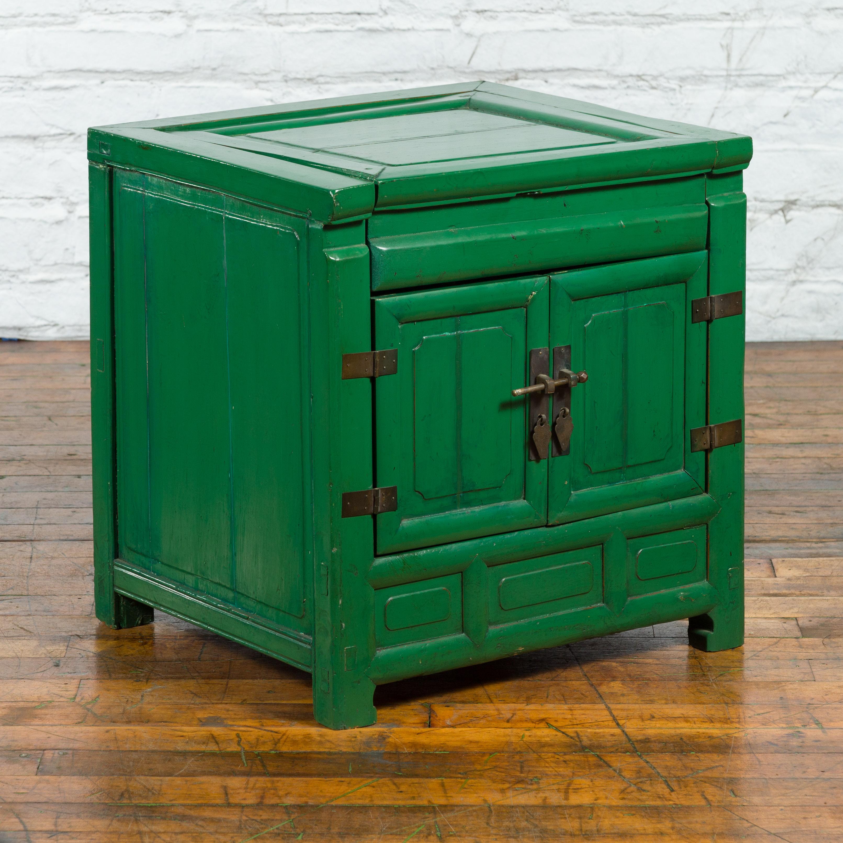 A Chinese Qing Dynasty period green lacquer bedside cabinet from the 19th century, with removable top and brass hardware. Created in China during the 19th century, this bedside cabinet attracts our attention with its green lacquer complimenting the