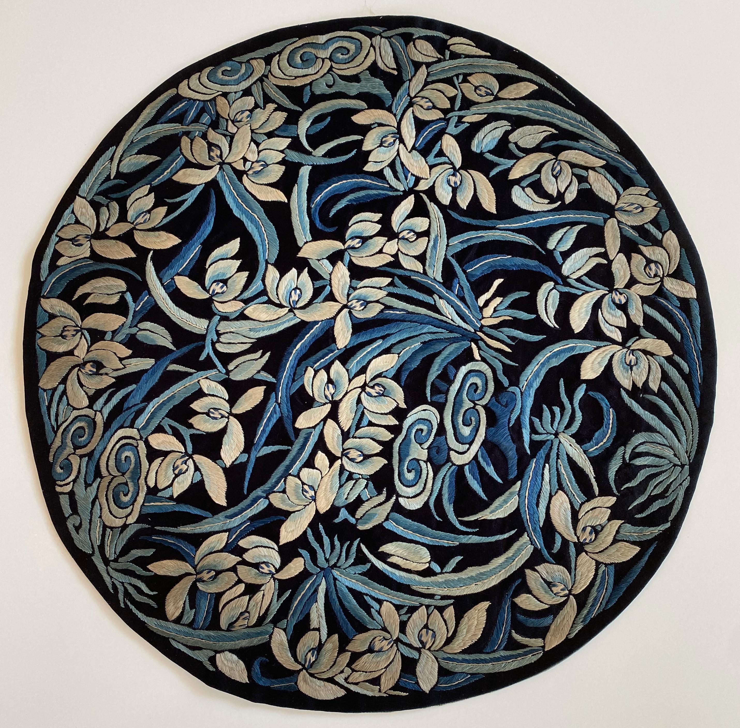 Qing Dynasty embroidered silk roundel depicting a profusion of irises. 

The flowers are embroidered in satin stitch in various shades of blue and ivory on a dark blue silk background. A few Lingzhi mushrooms -- the mushrooms of immortality -- are