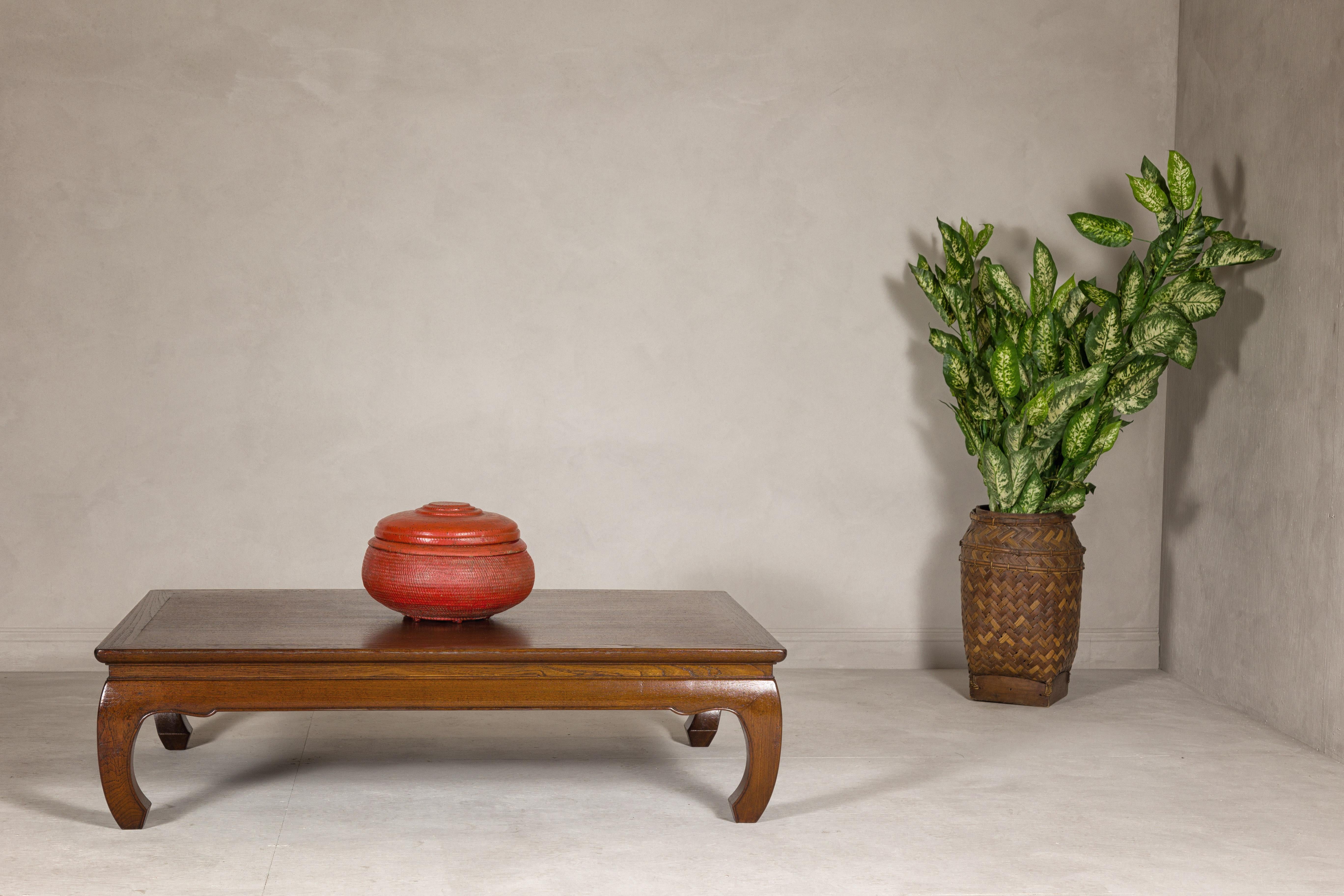 A late Qing Dynasty period long and low Kang coffee table from the early 20th century with chow legs and simply carved waisted apron. Born in the early 20th century during the late Qing Dynasty period, this exquisite long and low Kang coffee table