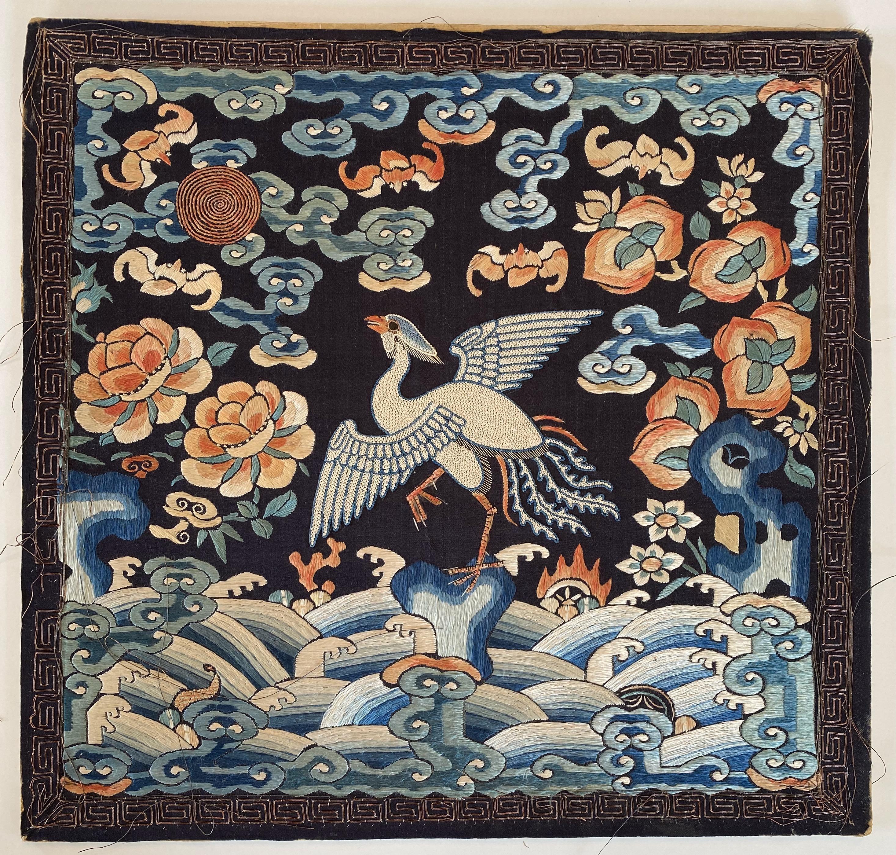 Qing Dynasty silk embroidery rank badge with silver pheasant.

This vividly-colored embroidery depicts a white pheasant on a dark blue background. The bird is shown with its wings outstretched, hovering above the sea. It faces a red-gold sun,