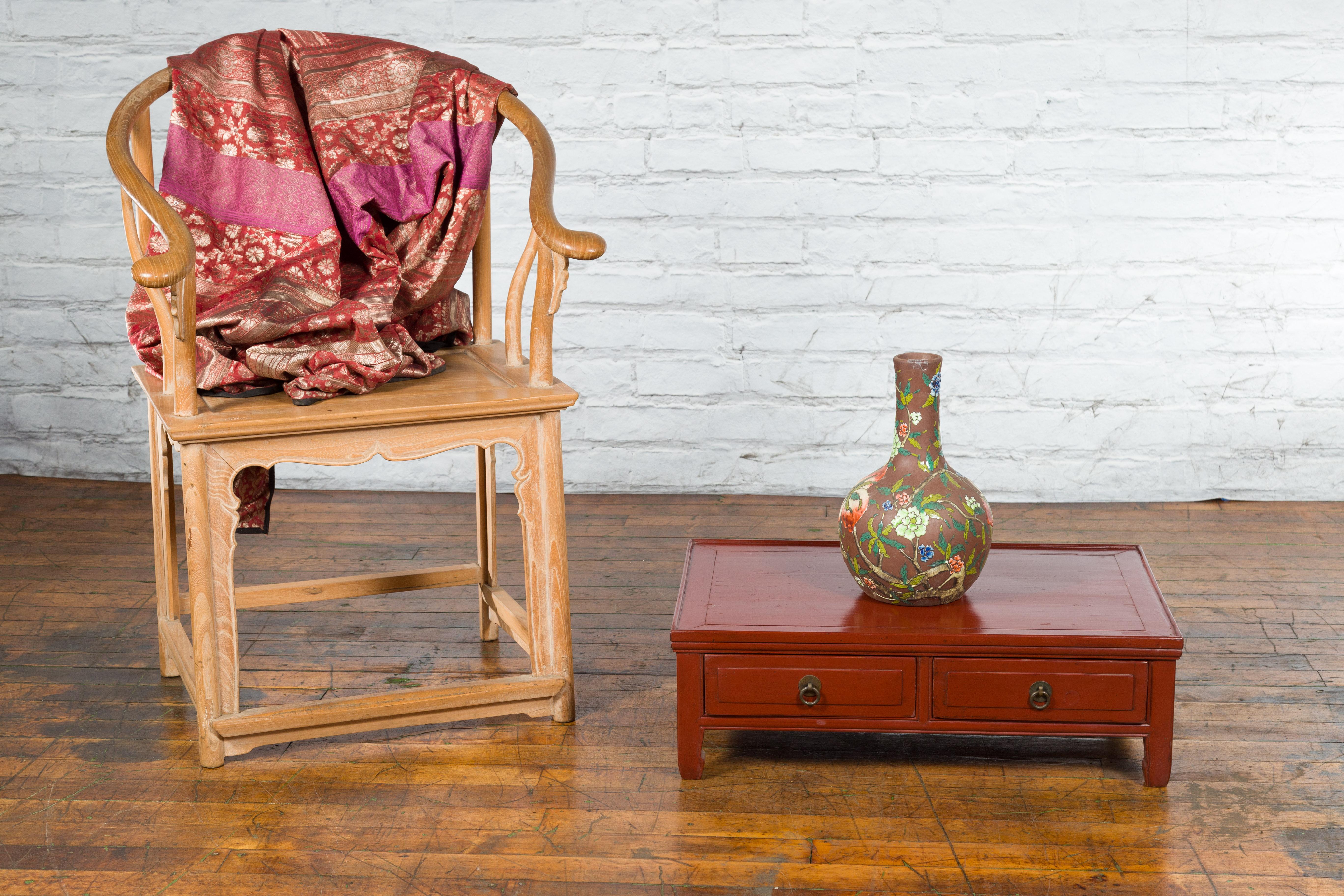Table basse kang en laque rouge, d'époque dynastie Qing, du 19ème siècle, avec deux tiroirs frontaux et des poignées rondes en laiton. Créée en Chine sous la dynastie Qing, cette table basse kang présente un plateau rectangulaire surmontant deux