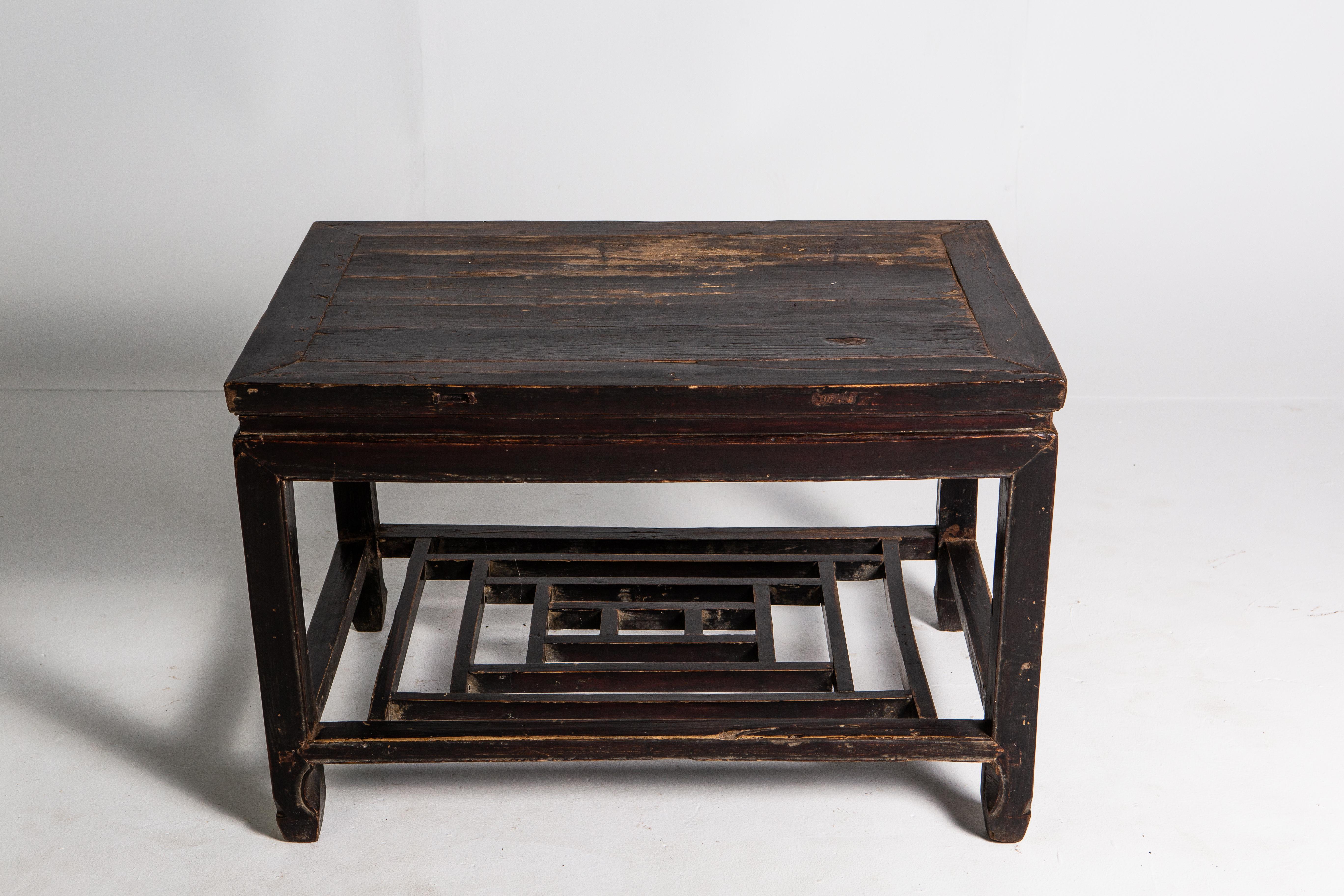 This elm side table dates to the middle-Qing dynasty and features a traditional latticework shelf. The piece retains its original patina and shows wear consistent with age and use.