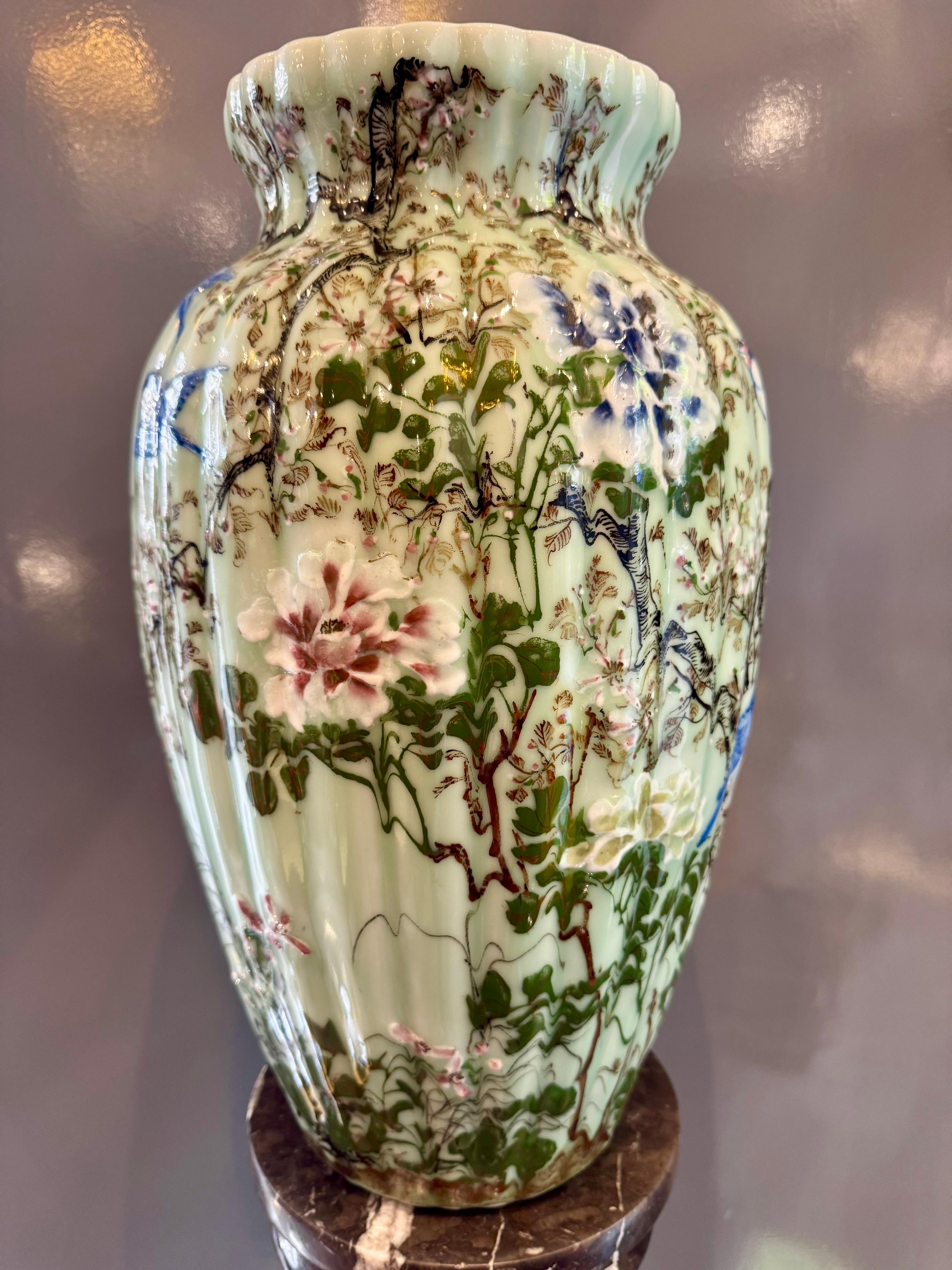 This exquisite Chinese porcelain vase combines the subtle sophistication of the traditional celadon glaze with the decorative opulence of the famille rose palette.
The soft jade-green background provides a luminous base for the vibrant floral and