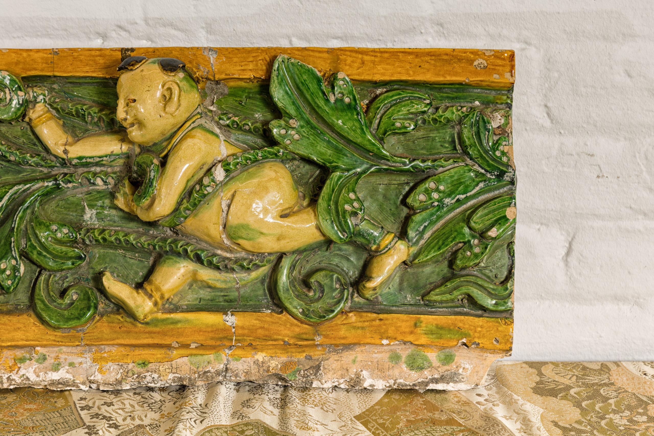 Glazed Qing Dynasty Tricolor Roof Fragment from a Temple Depicting a Boy Amidst Leaves For Sale