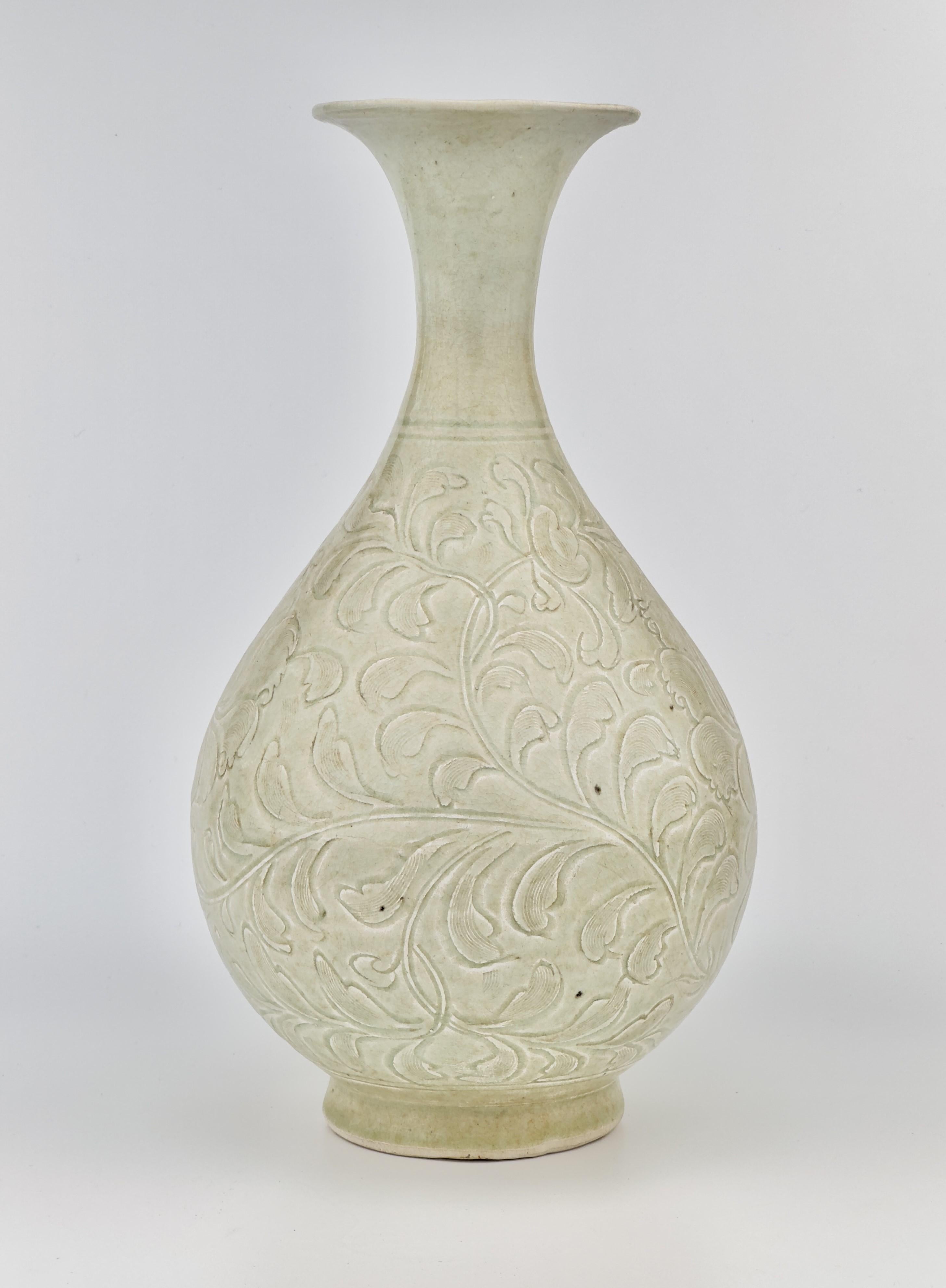Der mit einer feinen bläulichen Glasur überzogene Korpus ist vollständig mit einem eingeschnittenen Dekor aus eleganten Blattrollen und blühenden Lotusblumen verziert. Yuhuchunping