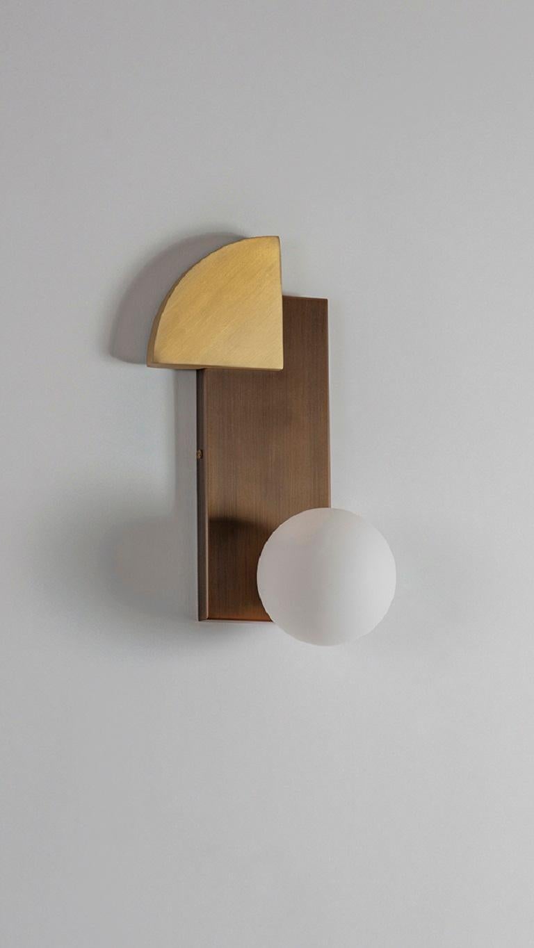 Quadrant and Sphere Wall Light by Square in Circle
Dimensions: D11.6 x W16.4 x H31 cm
Materials: Brushed brass/ medium bronze/ opaque glass.
Other finishes available.

This unique wall light is designed from three geometric forms: a quadrant circle,