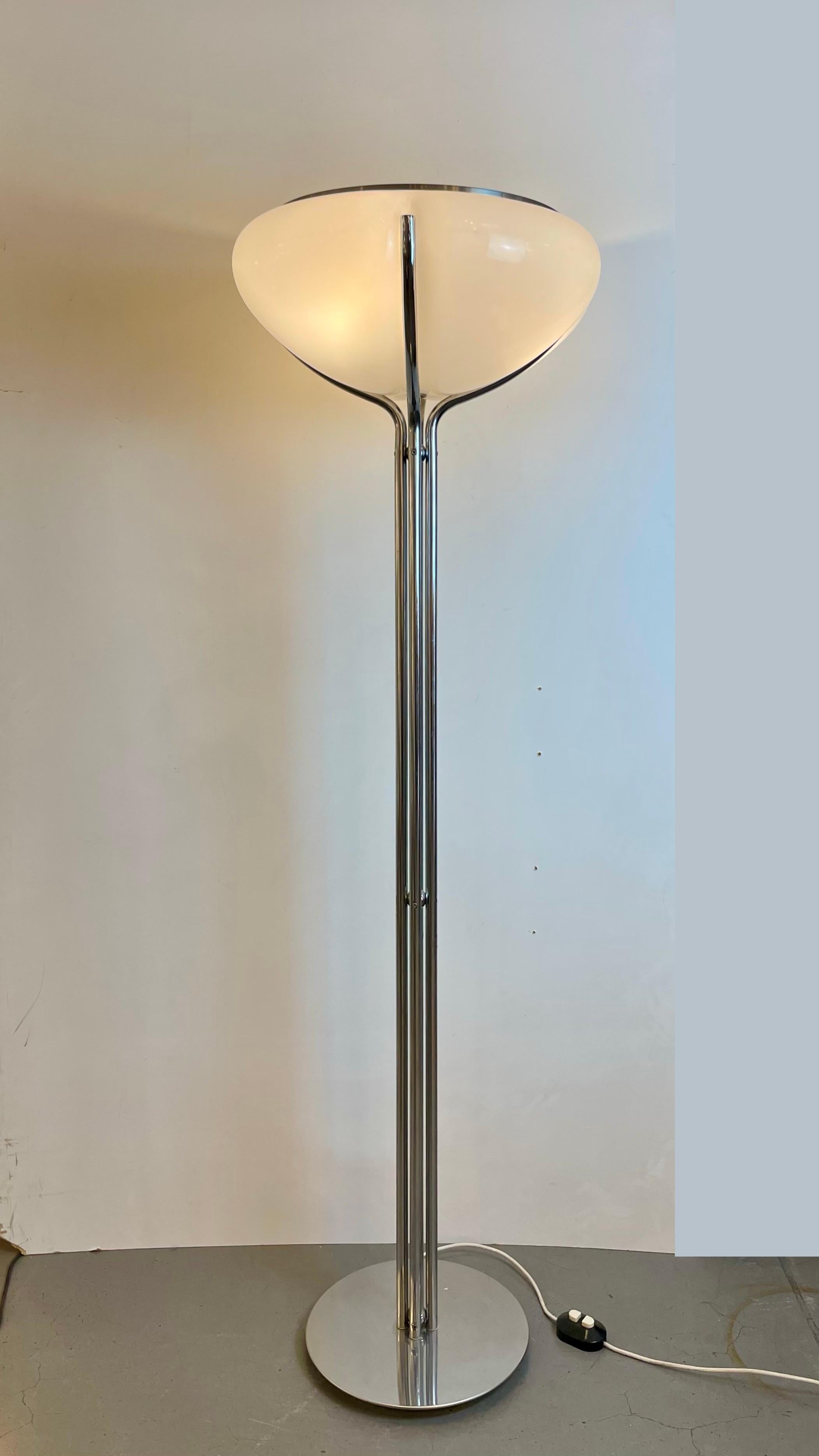 Iconica lampada da terra dell'era spaziale chiamata Quadriofoglio. Realizzata con quattro rami di metallo cromato che avvolgono un paralume in acrilico a forma di fiore di cotone, sormontato da un riflettore in alluminio spazzolato. Hanno due