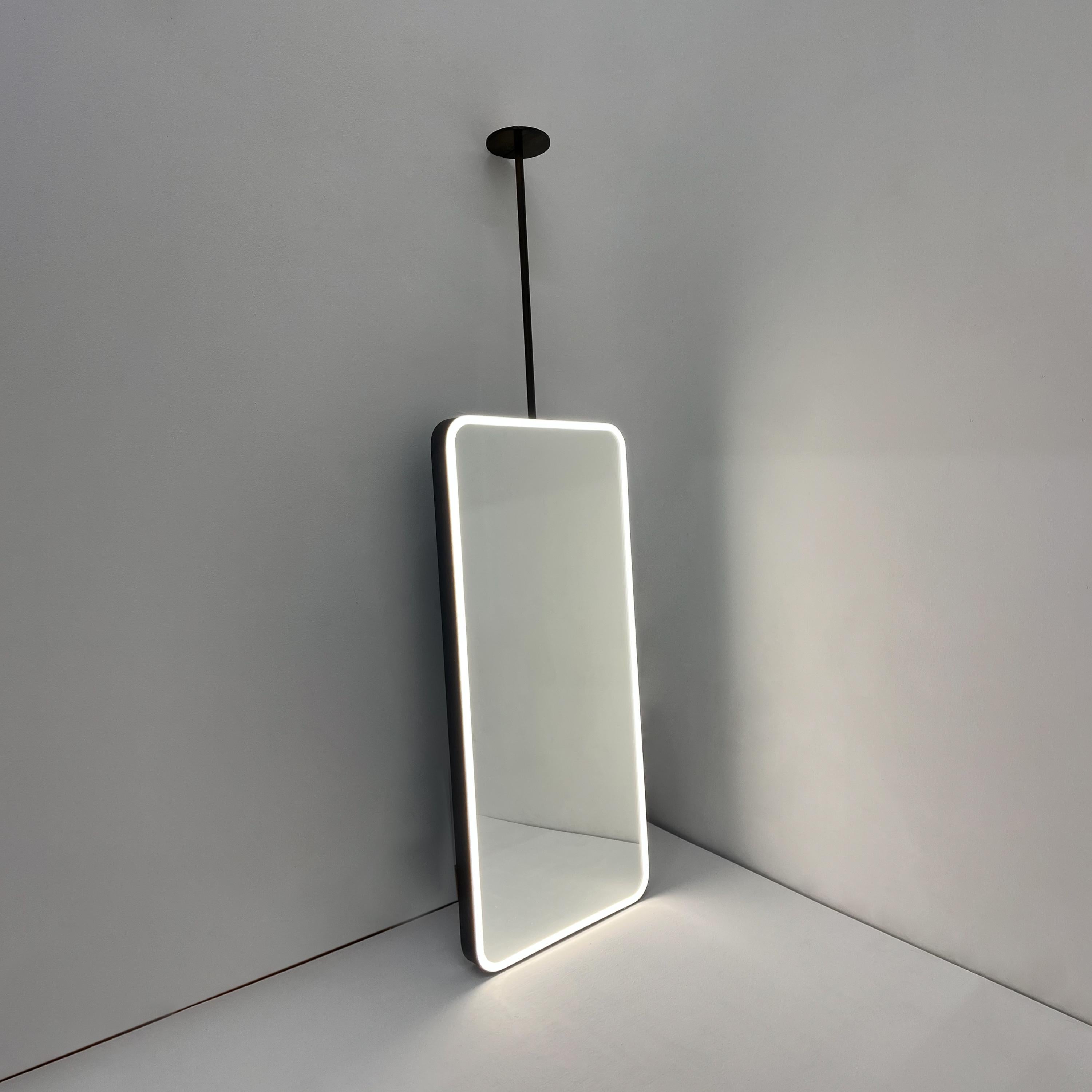 Miroir rectangulaire Quadris™ moderne suspendu au plafond avec éclairage frontal et cadre en laiton exquis et artisanal avec finition patinée bronze. Conçu et fabriqué à la main à Londres, au Royaume-Uni. Ce miroir est entièrement personnalisable