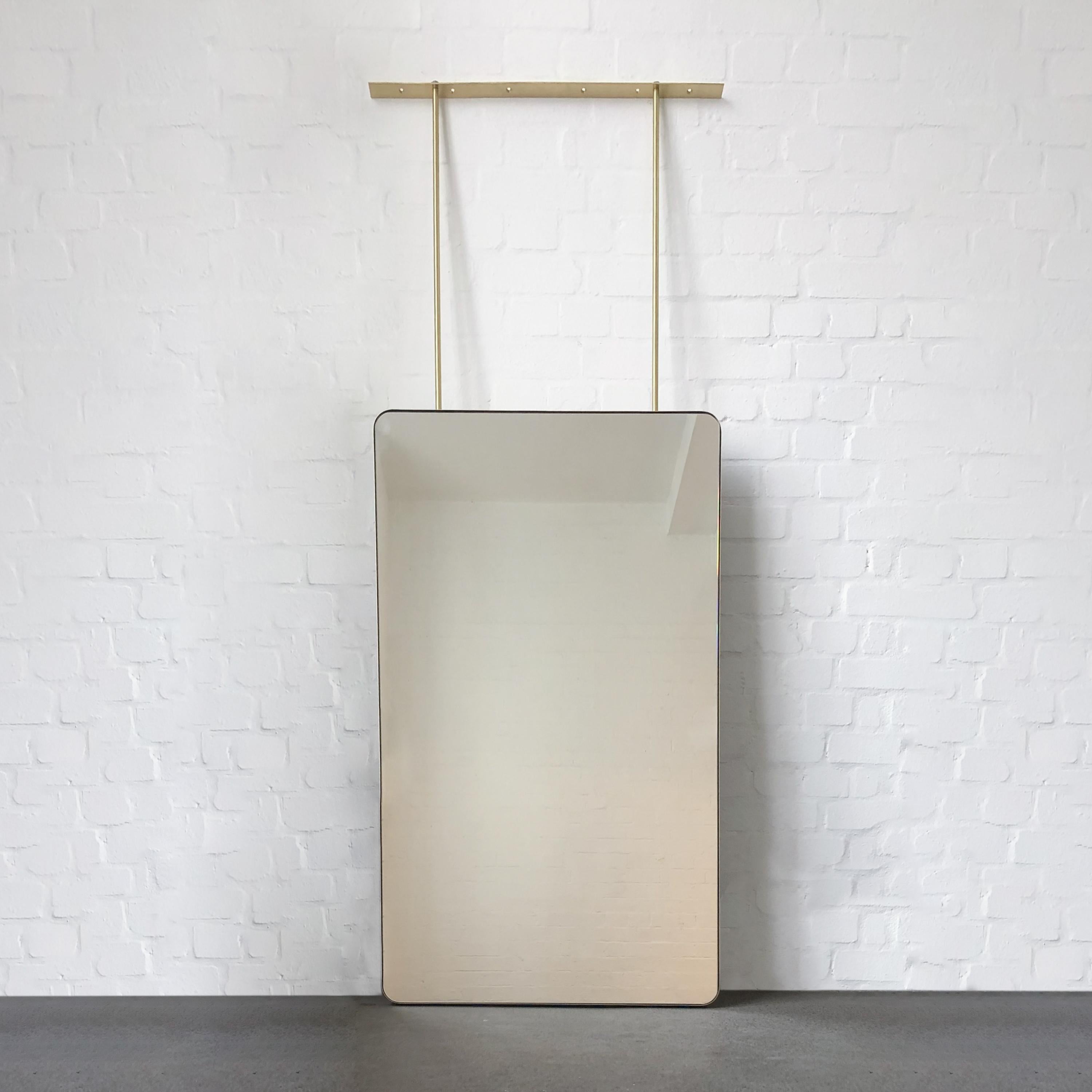 Oversized modern ceiling suspended Quadris™ rectangular mirror with a minimalist solid brushed brass frame and a white panel backing.

Our unique collections of ceiling suspended mirrors are designed and handcrafted in London, UK, and are therefore