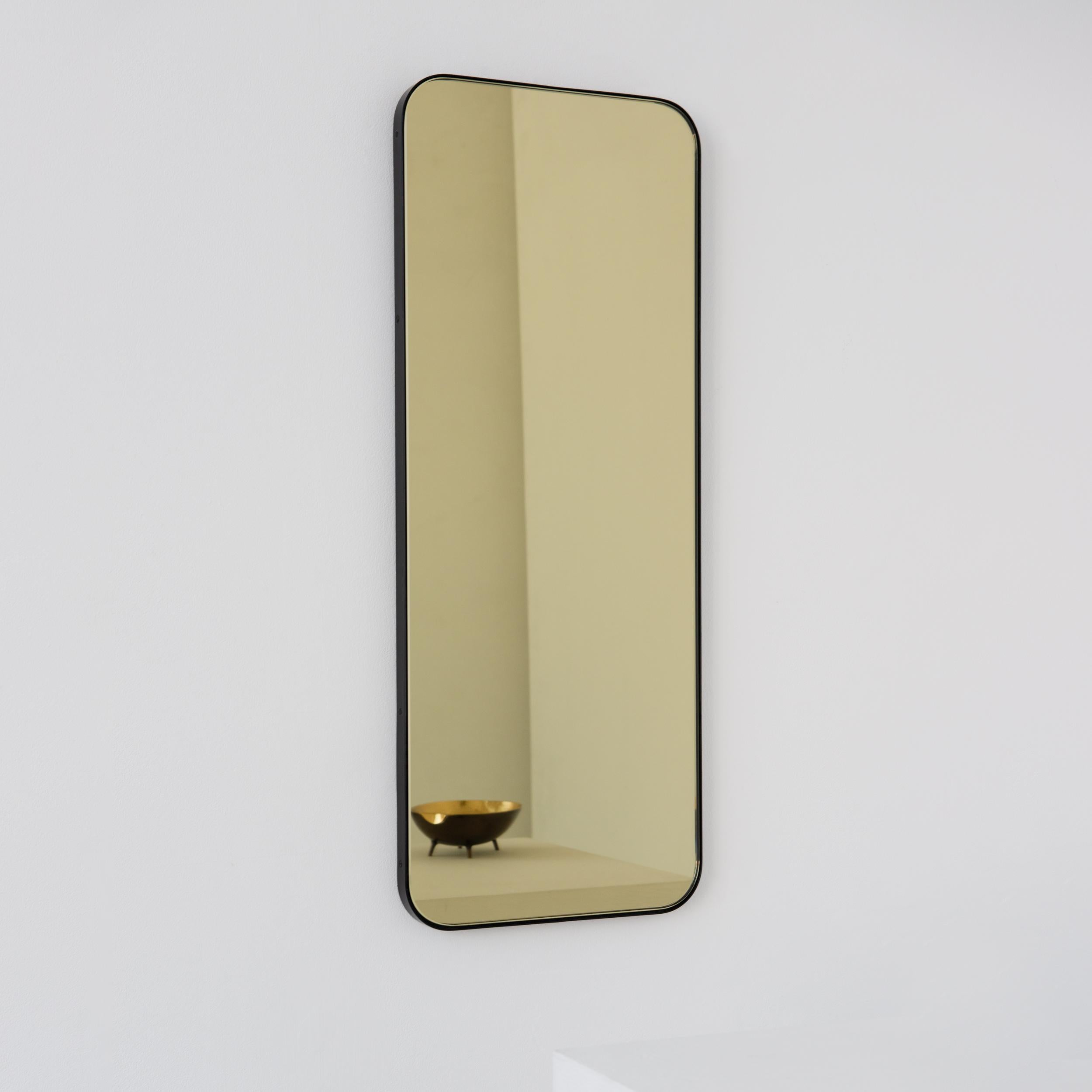 Miroir rectangulaire moderne teinté d'or avec un cadre noir élégant. Une partie de la charmante collection Quadris™, conçue et fabriquée à la main à Londres, au Royaume-Uni. 

Fourni avec une barre en z spécialisée pour une installation facile. Un