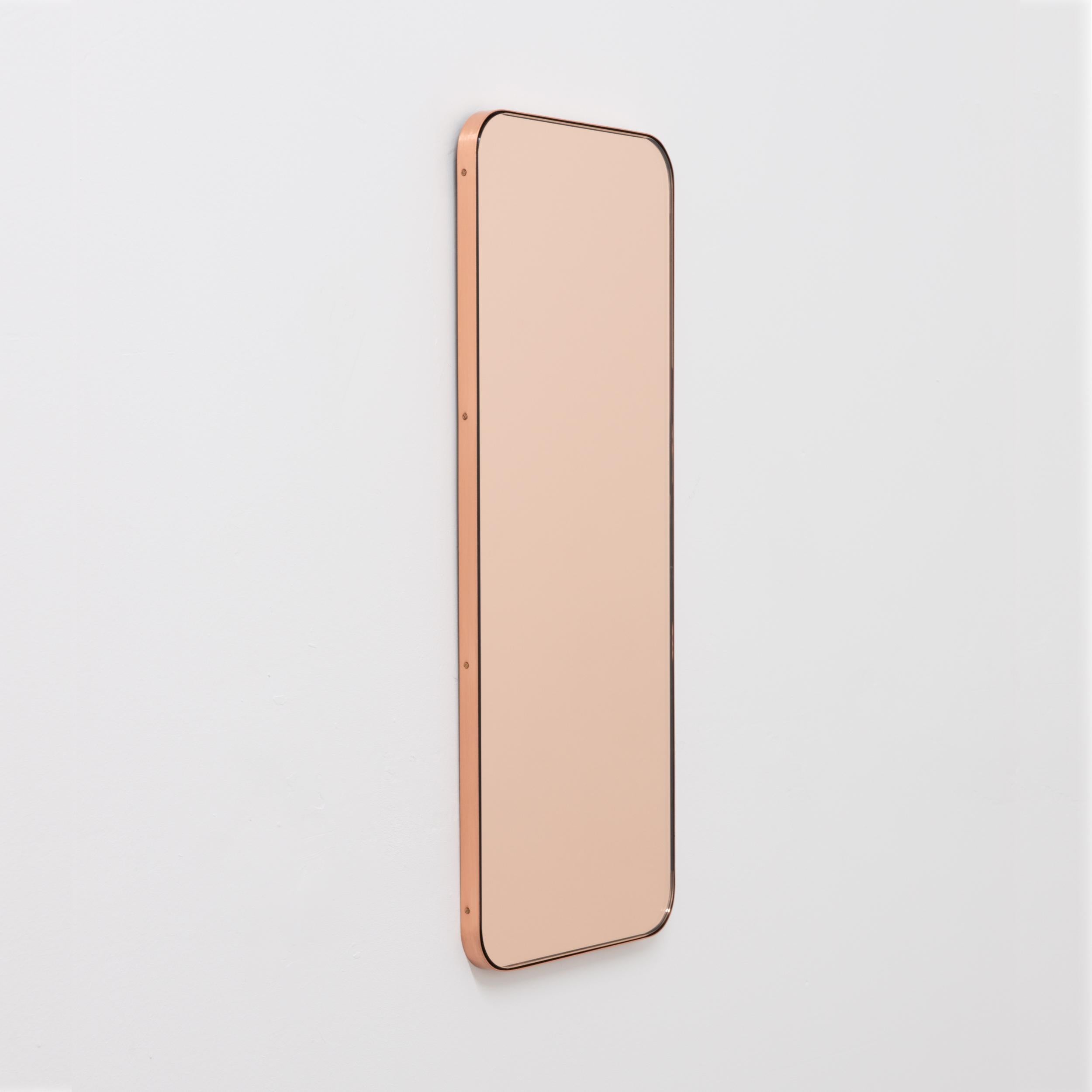 Minimalistischer, rechteckiger Spiegel mit einem eleganten, schlanken Rahmen aus gebürstetem Kupfer. Die Details und die Verarbeitung, einschließlich der sichtbaren verkupferten Schrauben, unterstreichen die handwerkliche Qualität des Spiegels, ein