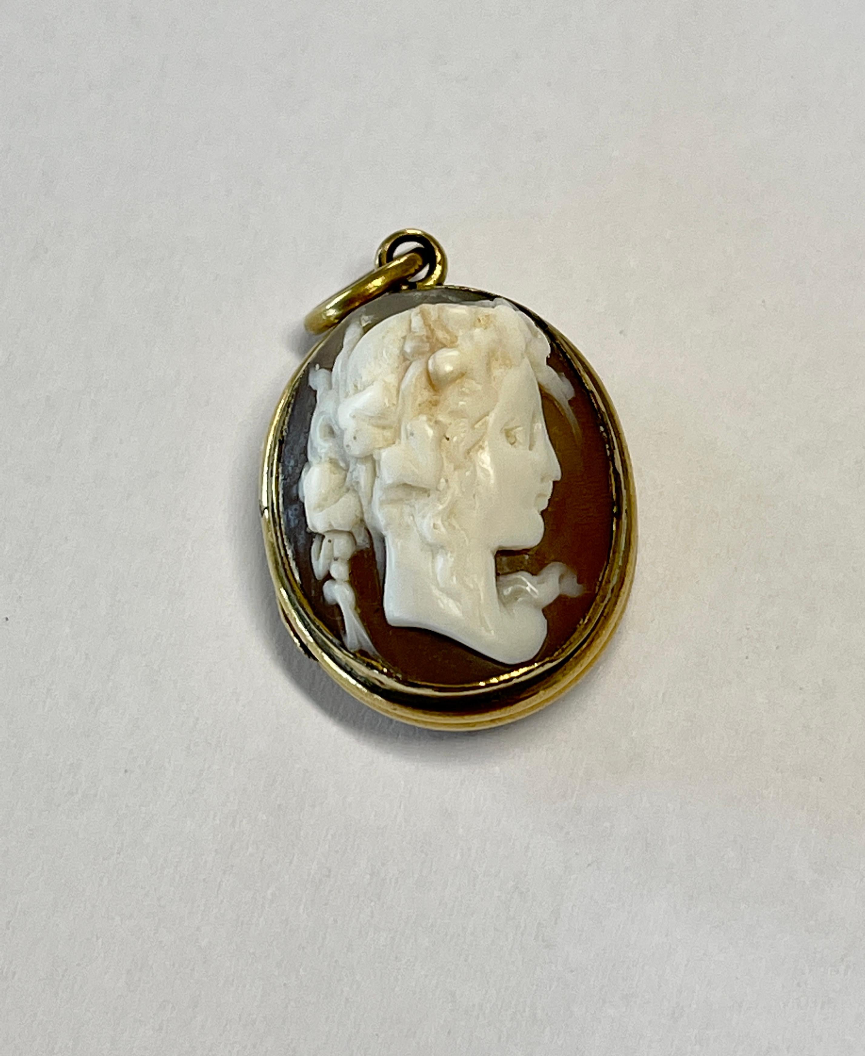 This is a dainty, Cameo locket from the Victorian Era c1880s.  

It features a romantic lady with flowers in her wispy hair.  The small Cameo sits in high relief and is carved in conch shell.  The reverse if fitted with bloodstone which was a symbol