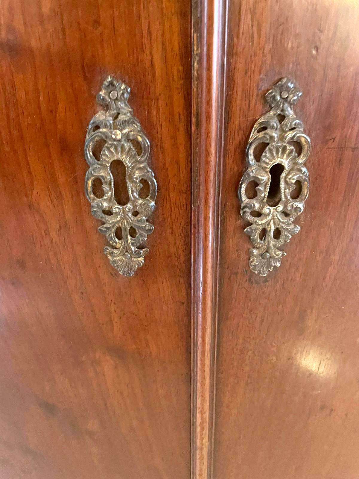 Armadietto angolare in mogano di qualità del XVIII secolo, con una deliziosa cornice dentale sagomata sopra un fregio in legno di raso. La coppia di ante ad arco in prugna si apre per rivelare un interno attrezzato con quattro ripiani e tre