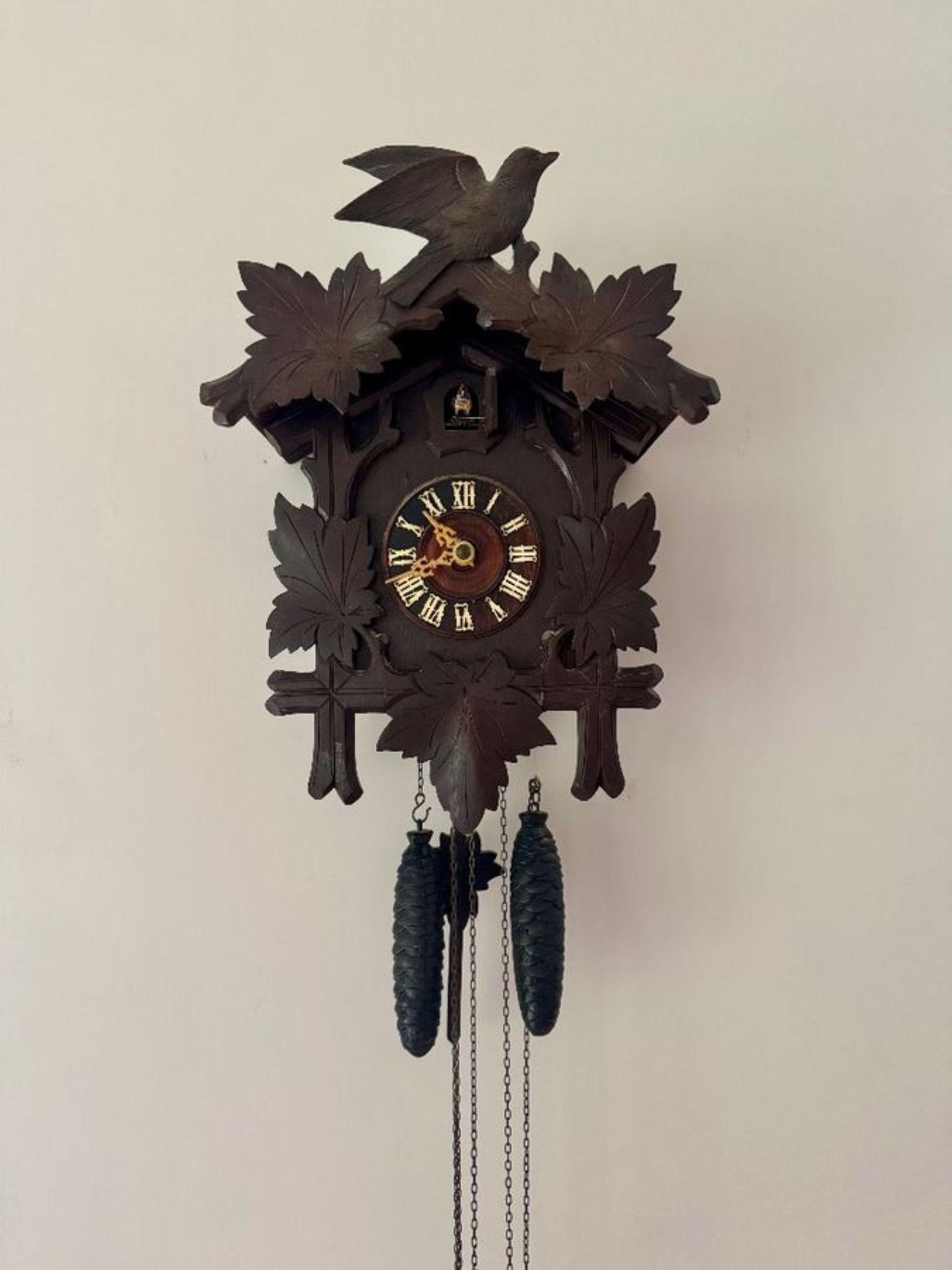 Antico orologio a cucù della Black Forest di qualità, con un antico orologio a cucù tradizionale decorato con foglie intagliate e un uccello nella parte superiore e foglie ai lati del quadrante circolare con numeri romani bianchi e lancette ornate