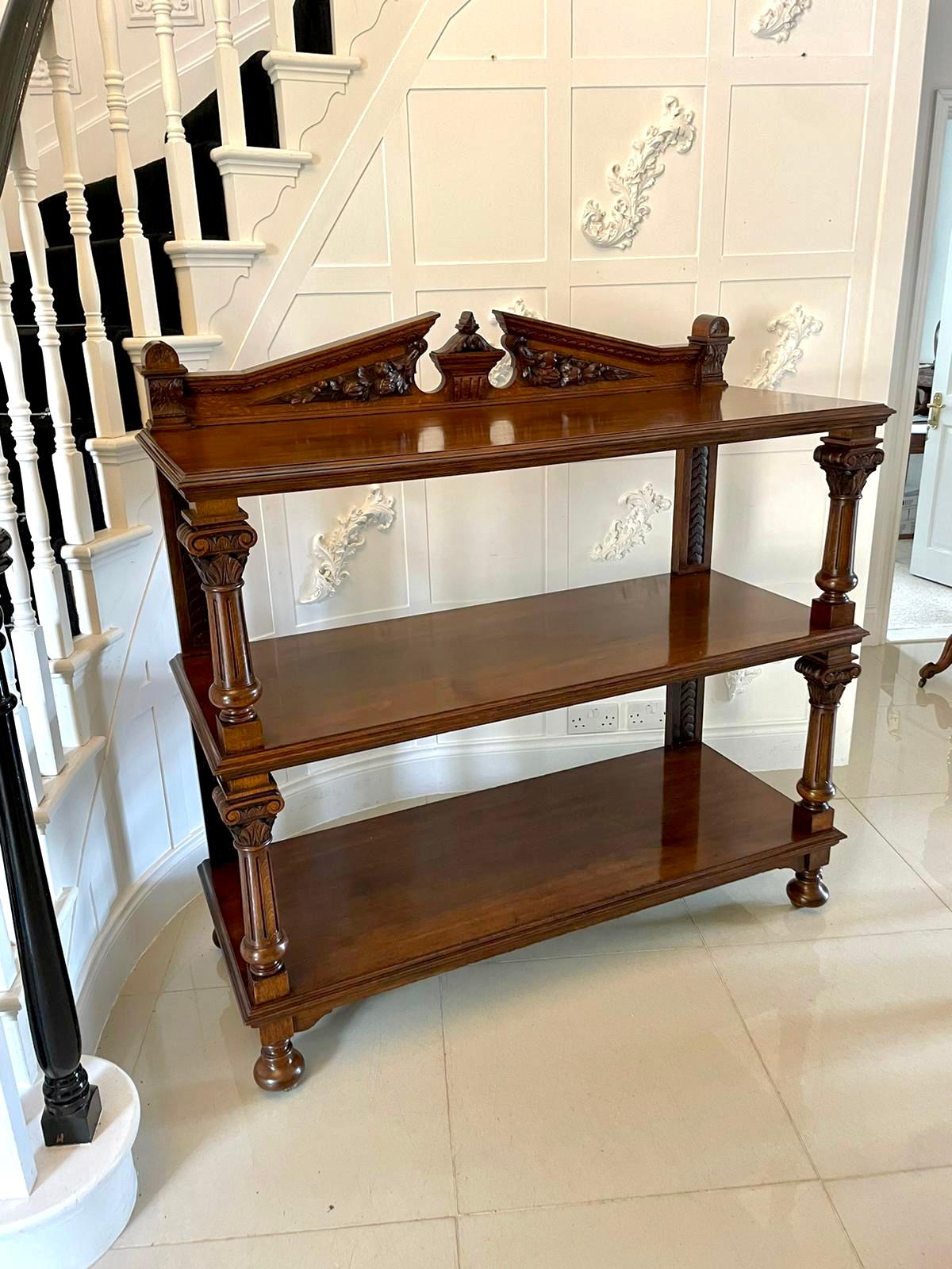 Quality antique carved oak dumbwaiter having a pomegranate carved broken arch pediment and three tiers between fluted carved columns, raised on bun feet with original castors.

 A superior Victorian example displaying a fabulous colour and first