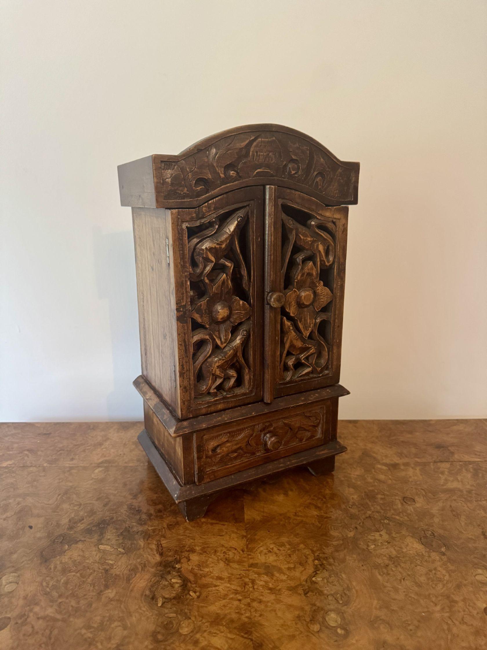 Quality antique carved oak tabletop cabinet, having a quality carved oak tabletop cabinet with a arched shaped top above a pair of carved oak doors, opening to reveal four fitted drawers. 

D. 1920