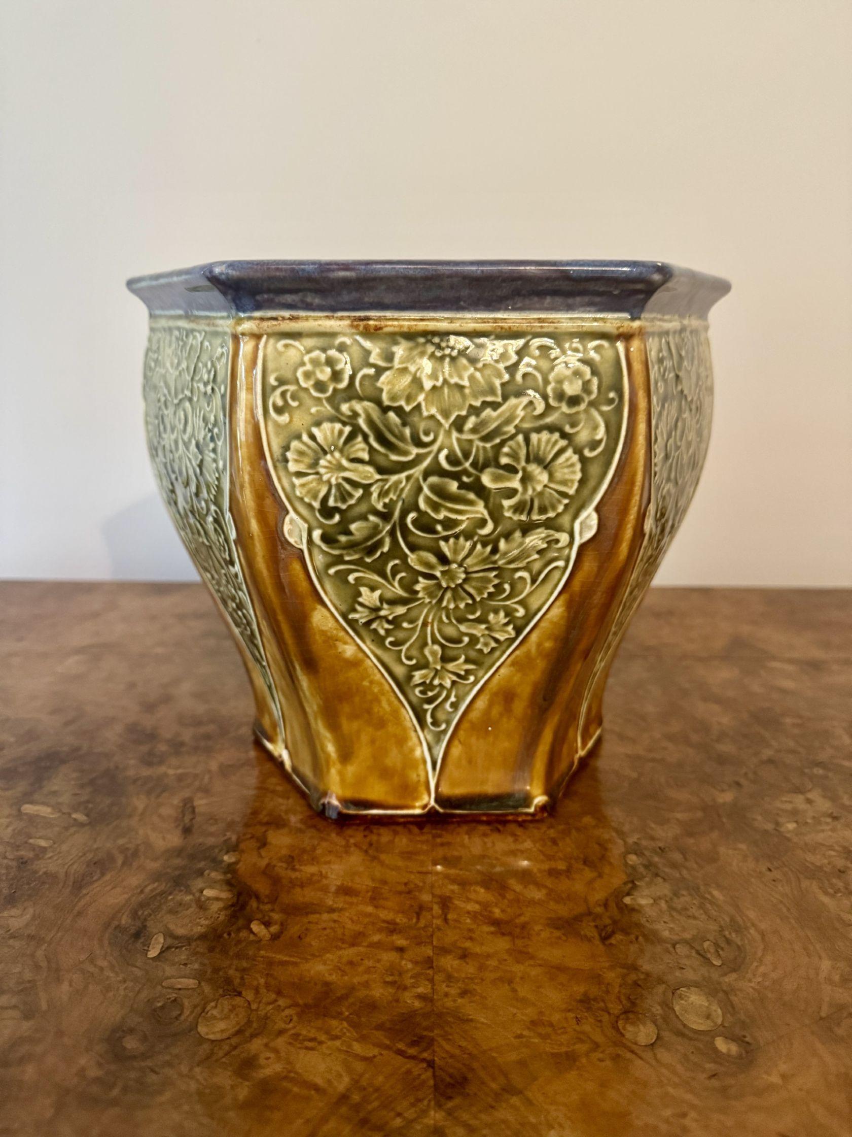 Jardinière hexagonale émaillée de qualité Doulton Lambeth, présentant un bord supérieur légèrement évasé peint à la main en bleu au-dessus d'un corps légèrement incurvé, décoré de panneaux brun doré dans des sections vertes ornées de motifs floraux