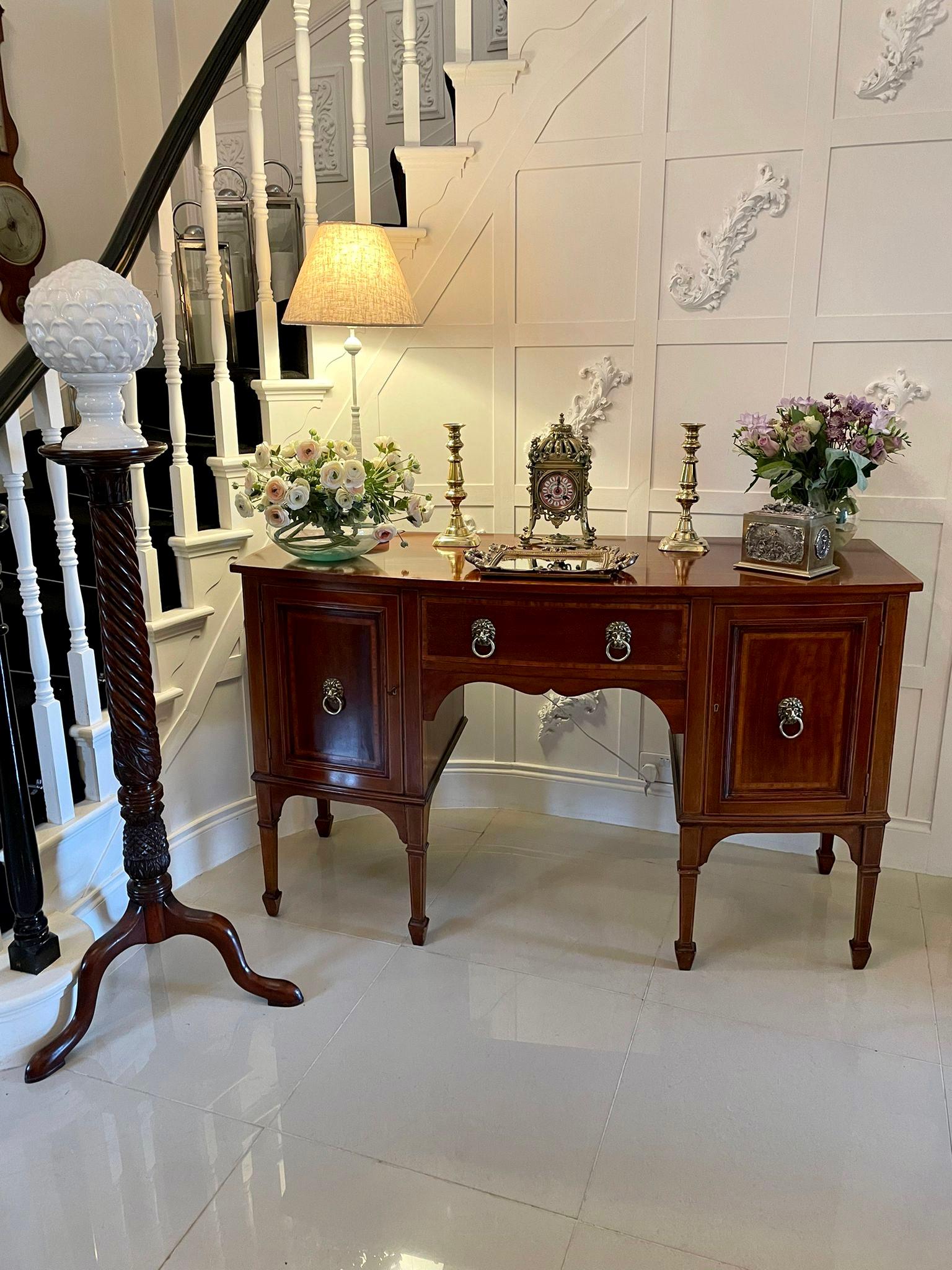 Quality antique Edwardian inlaid mahogany bow fronted sideboard having a quality mahogany top with pretty satinwood crossbanding, mahogany inlaid drawer with attractive original brass lions head handles to the centre flanked by two bow fronted