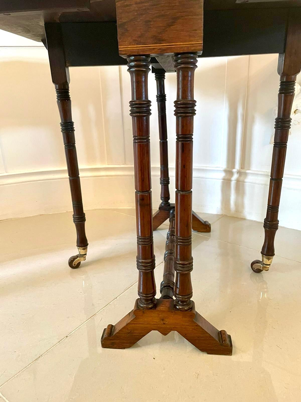 Quality antique Edwardian inlaid rosewood Sutherland table having a quality and beautifully inlaid rosewood top with two drop leaves and a moulded edge. It stands on turned end supports with two swing out gatelegs with original castors, shaped feet
