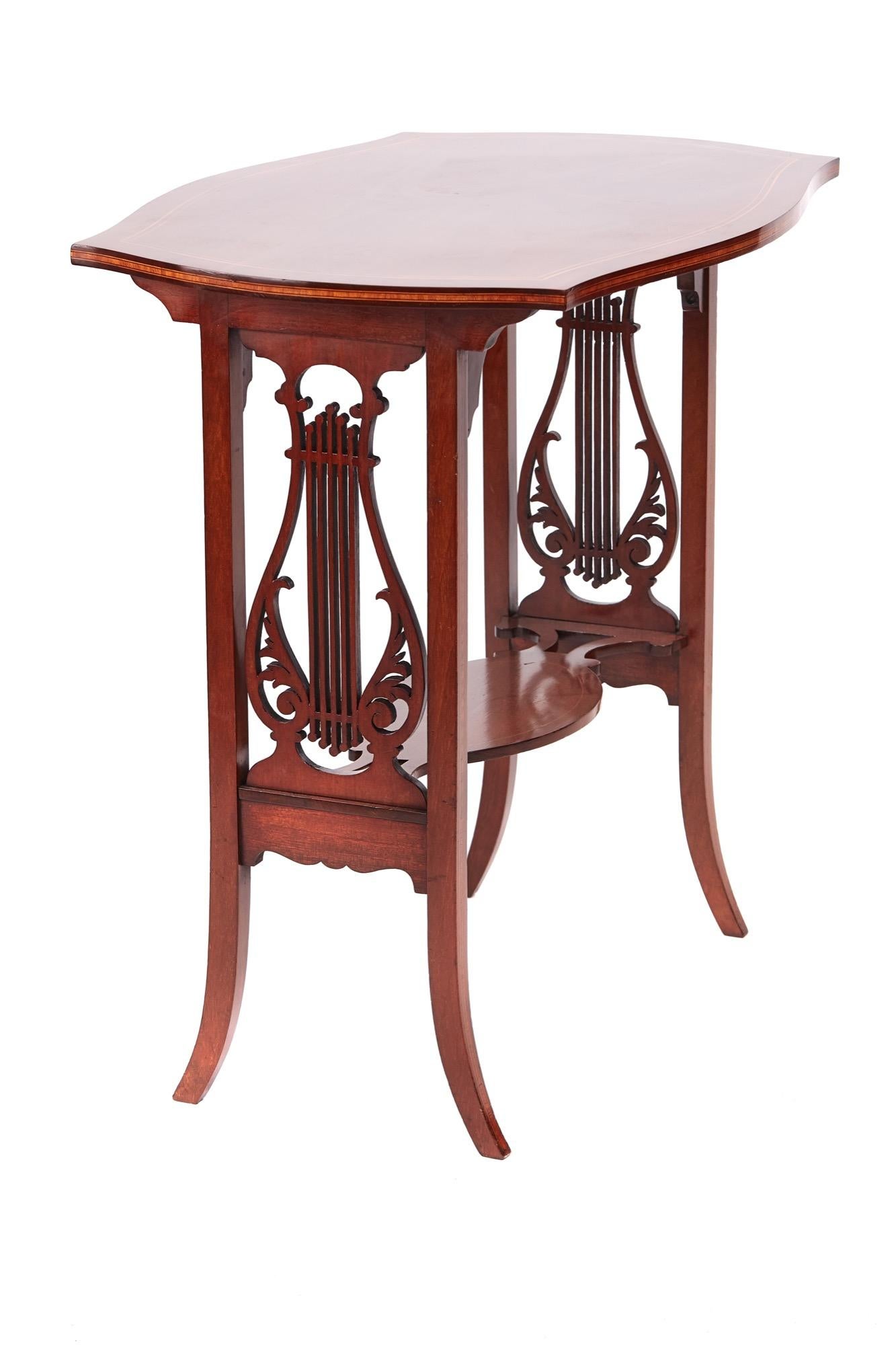 Quality Edwardian mahogany inlaid lamp table having an outstanding quality shaped mahogany top with satinwood inlay supported by a delightful pierced lyre shaped end. It is standing on four mahogany inlaid shaped legs and united by a shaped