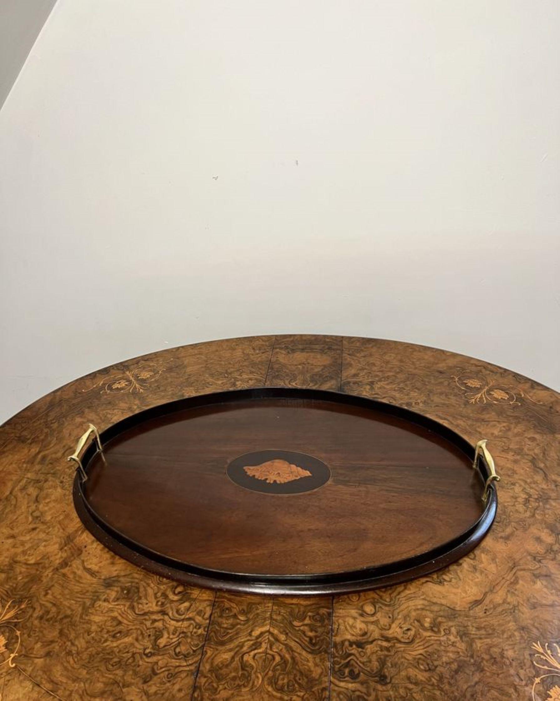 Quality antique Edwardian mahogany inlaid oval tea tray having a quality mahogany inlaid shell to the centre of the tray with a gallery edge and the original brass carrying handles

D. 1900