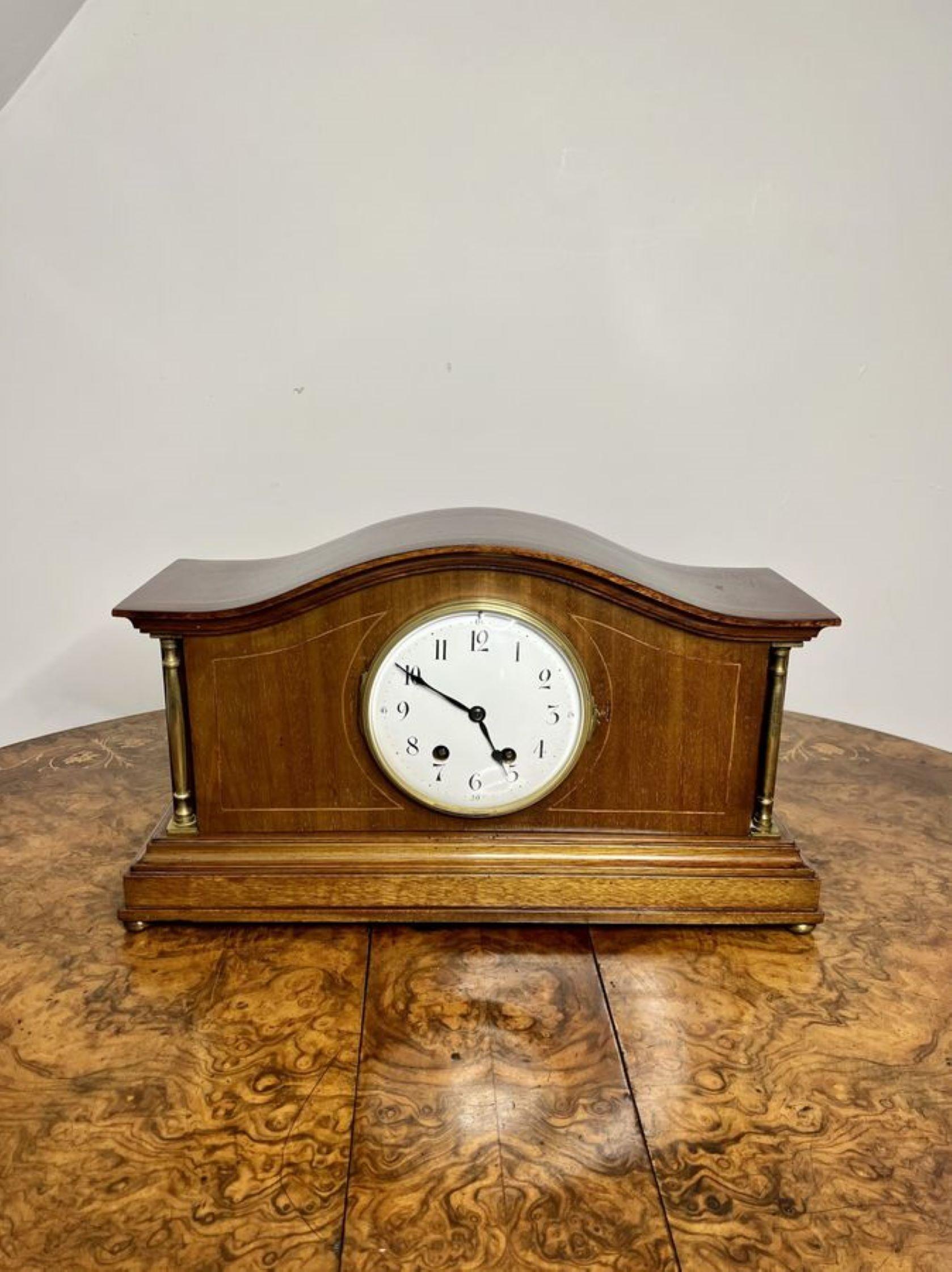 Quality antique Edwardian walnut mantle clock having a quality antique Edwardian walnut mantle clock having a white enamel dial with Arabic numerals and the original hands, a walnut case with brass columns raised on brass ball feet, having an eight