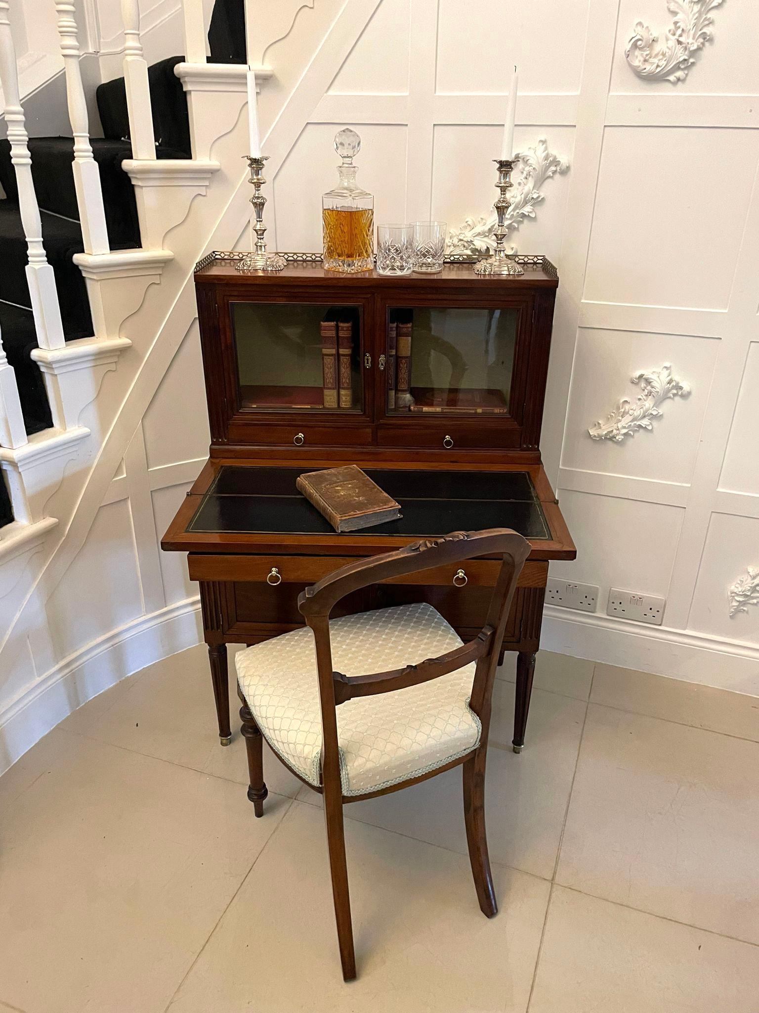 Escritorio abatible de caoba francesa antigua de calidad que tiene la bonita galería original de latón, dos puertas acristaladas, dos cajones con tiradores originales de latón. La base cuenta con una superficie abatible para escribir, un cajón largo