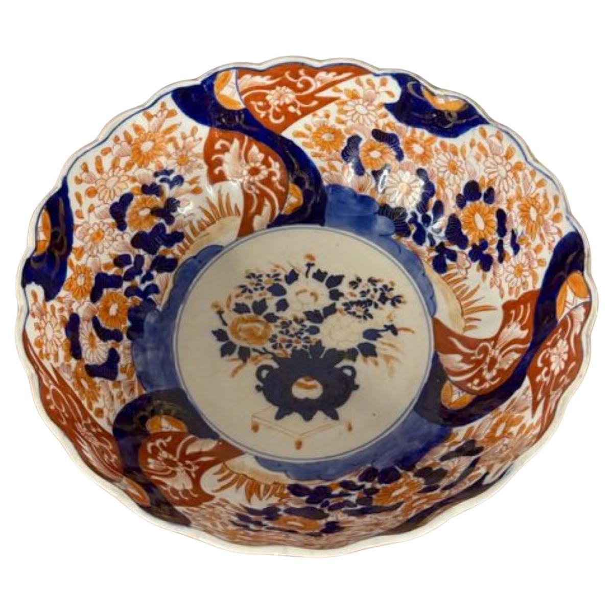 Cuenco imari japonés antiguo de calidad, con borde ondulado, decorado con una cesta de flores en el centro rodeada de flores, hojas y volutas, pintado a mano en vibrantes colores rojo, azul y blanco. 

D. 1900
