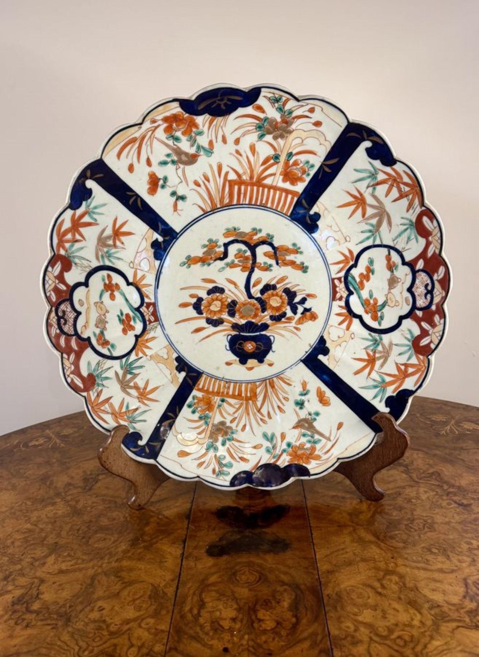 Chargeur imari japonais ancien de qualité, ayant un bord festonné, décoré d'un panier de fleurs au centre entouré de panneaux avec des fleurs, des arbres et des oiseaux peints à la main en rouge, bleu, brun, vert et blanc.

D. 1900