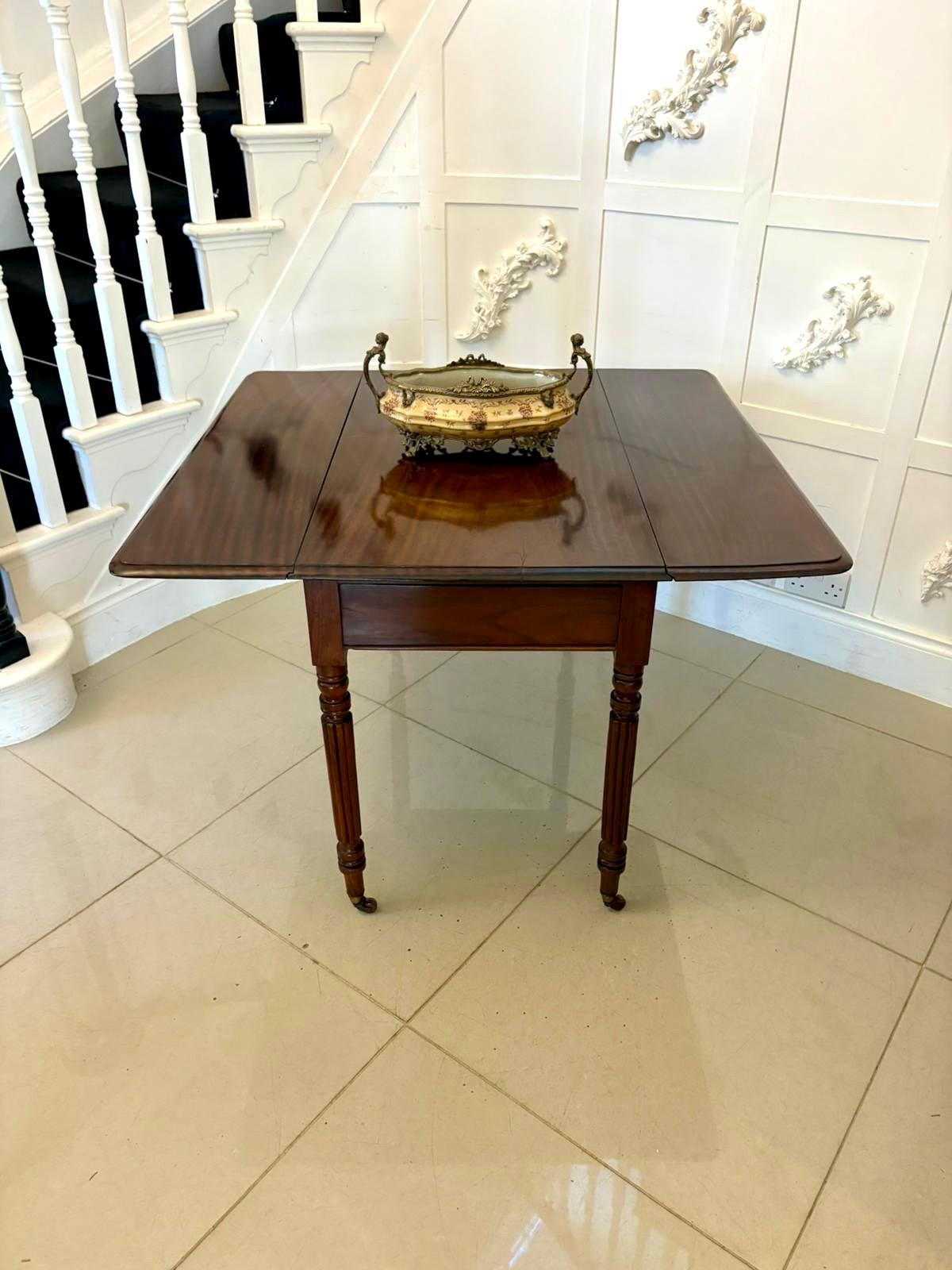 Une table Pembroke en acajou de style Regency, de forme élégante et compacte. La table est dotée d'un plateau en acajou magnifiquement figuré et de deux abattants qui s'ouvrent pour créer une surface généreuse, parfaite pour les petits repas, le